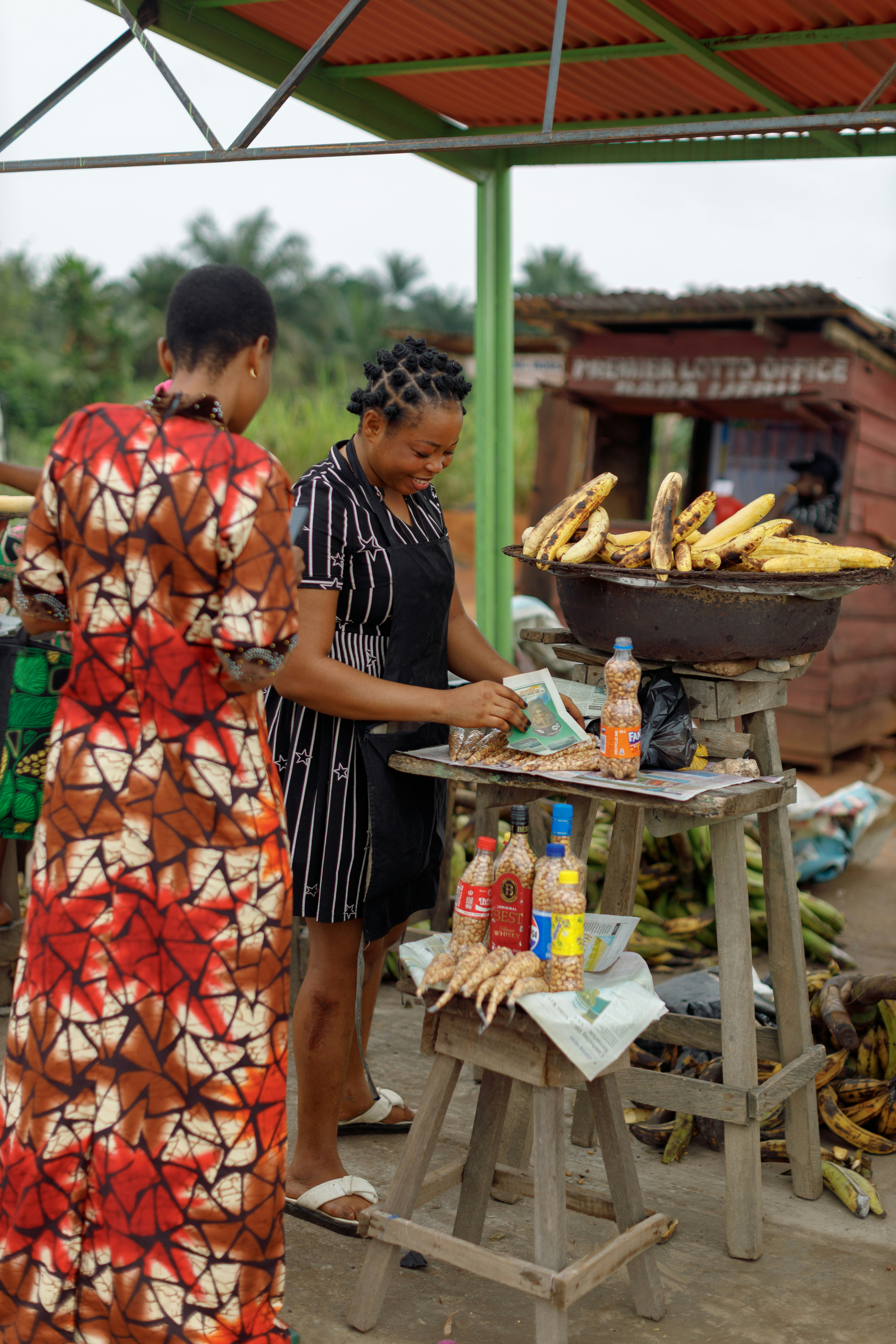 Two women at a food stall with plantains