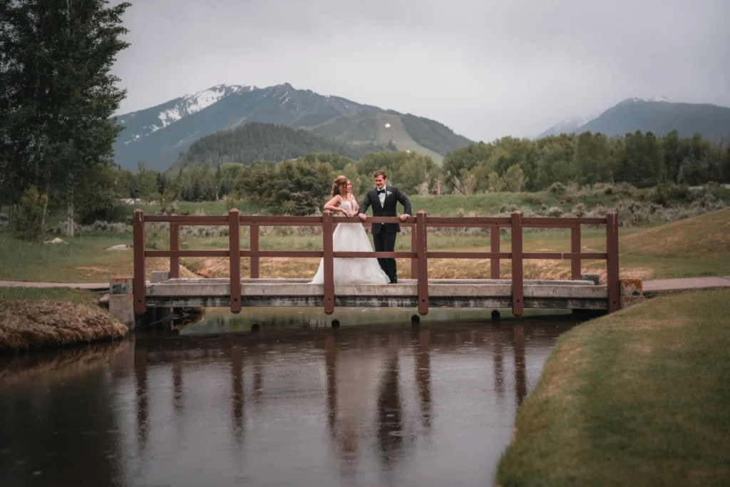Newlyweds embracing on a wooden bridge over a pond