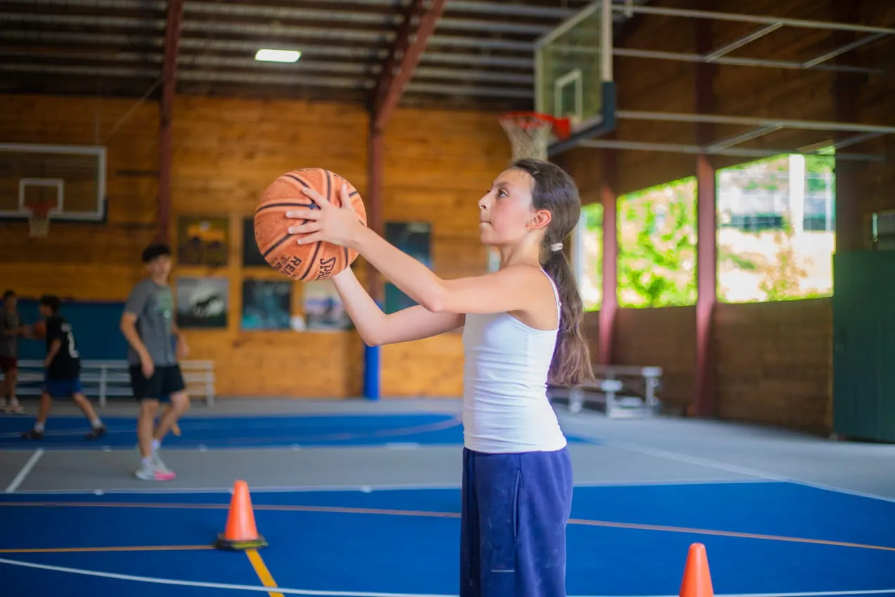 Camper shooting a basketball in the gym at Camp Lenox