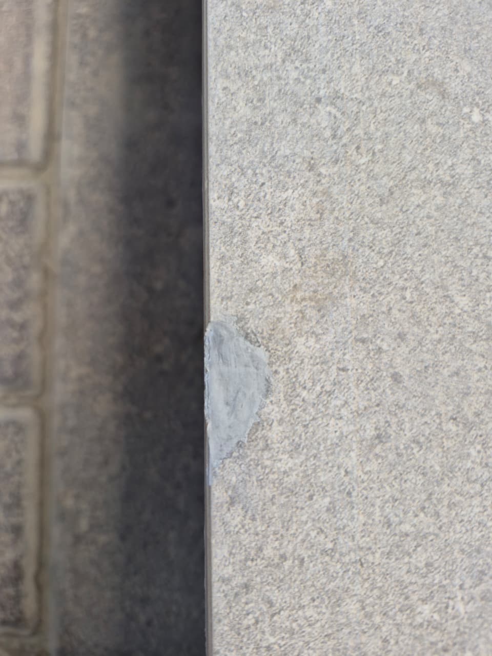 Chipped stone-effect porcelain coping edge before repair in Dubai