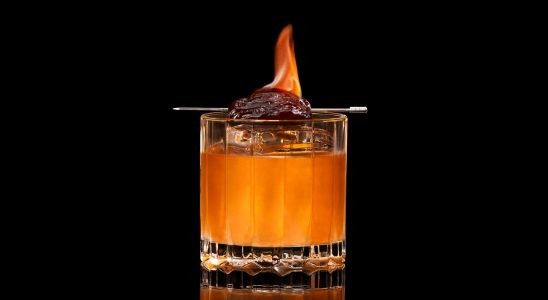 A closeup of a Savory, Winter Holiday Wish drink against a dark background.