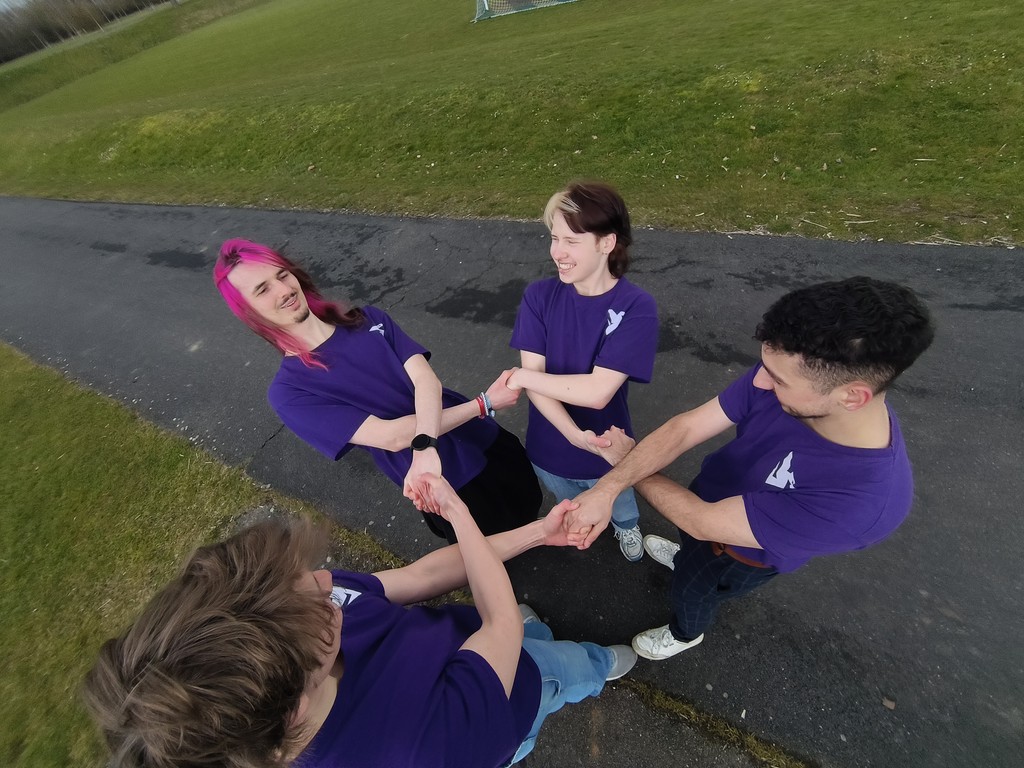 DDI team in a group huddle holding on to each other outside