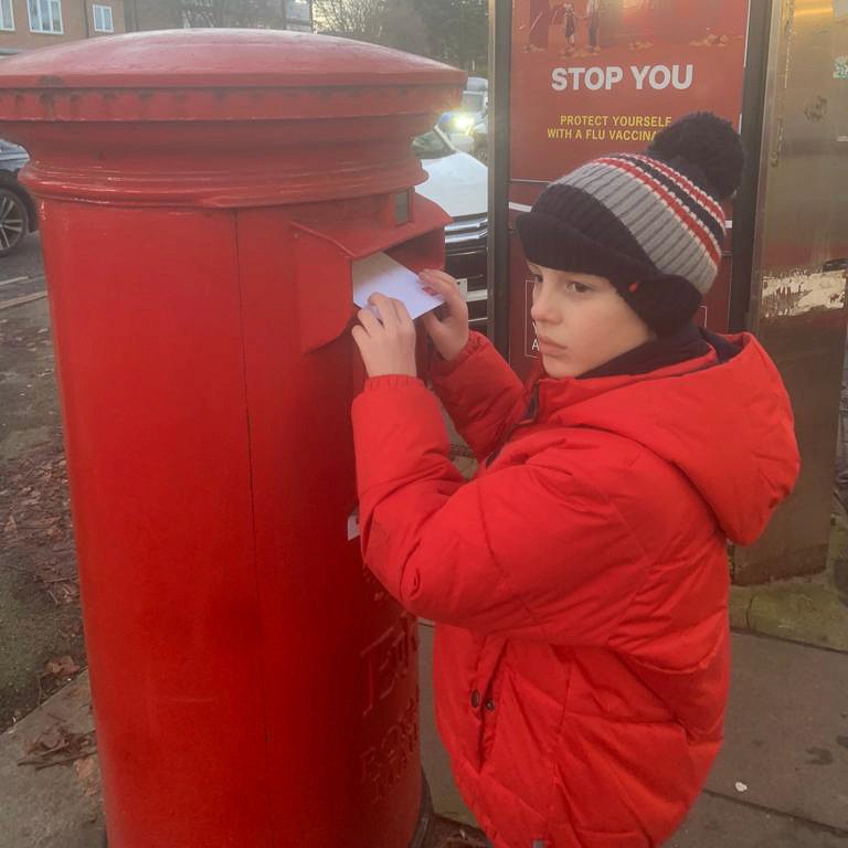 A child is posting letters into a large postbox