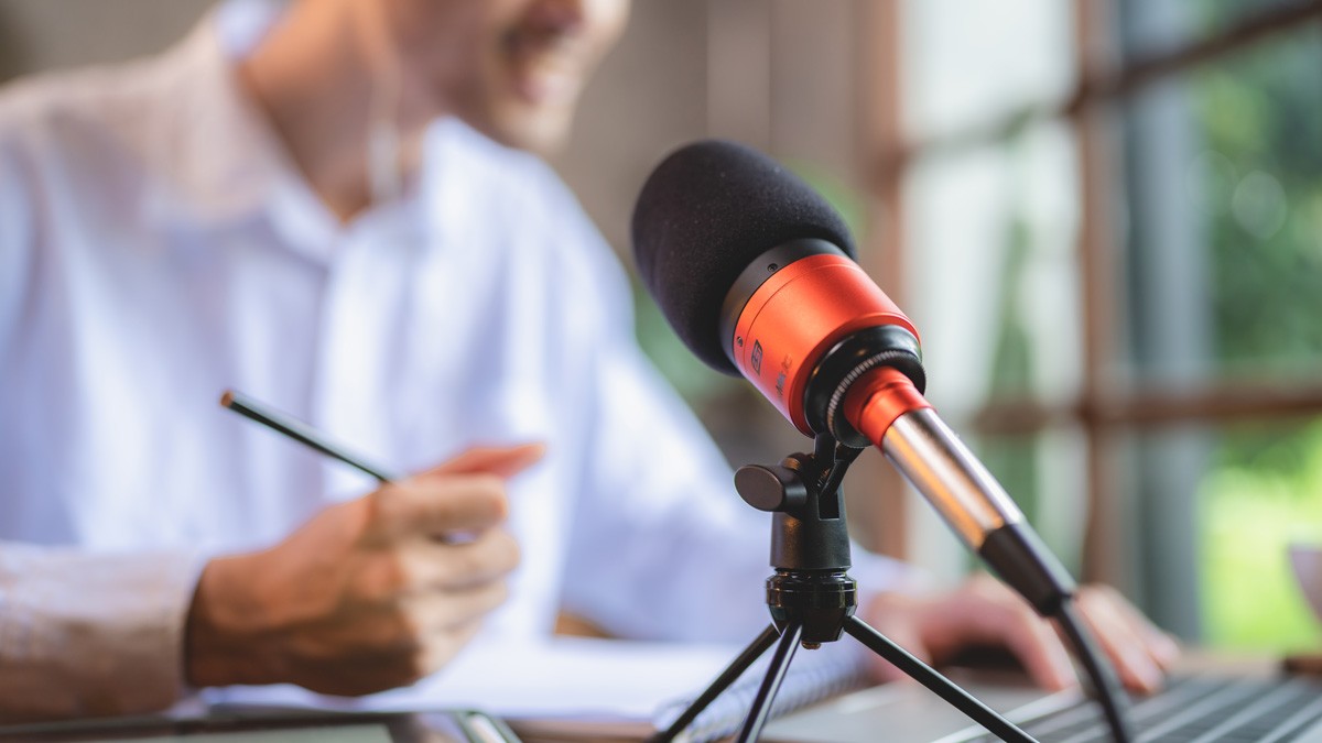 A workshop facilitator speaking to a microphone during a hybrid meeting
