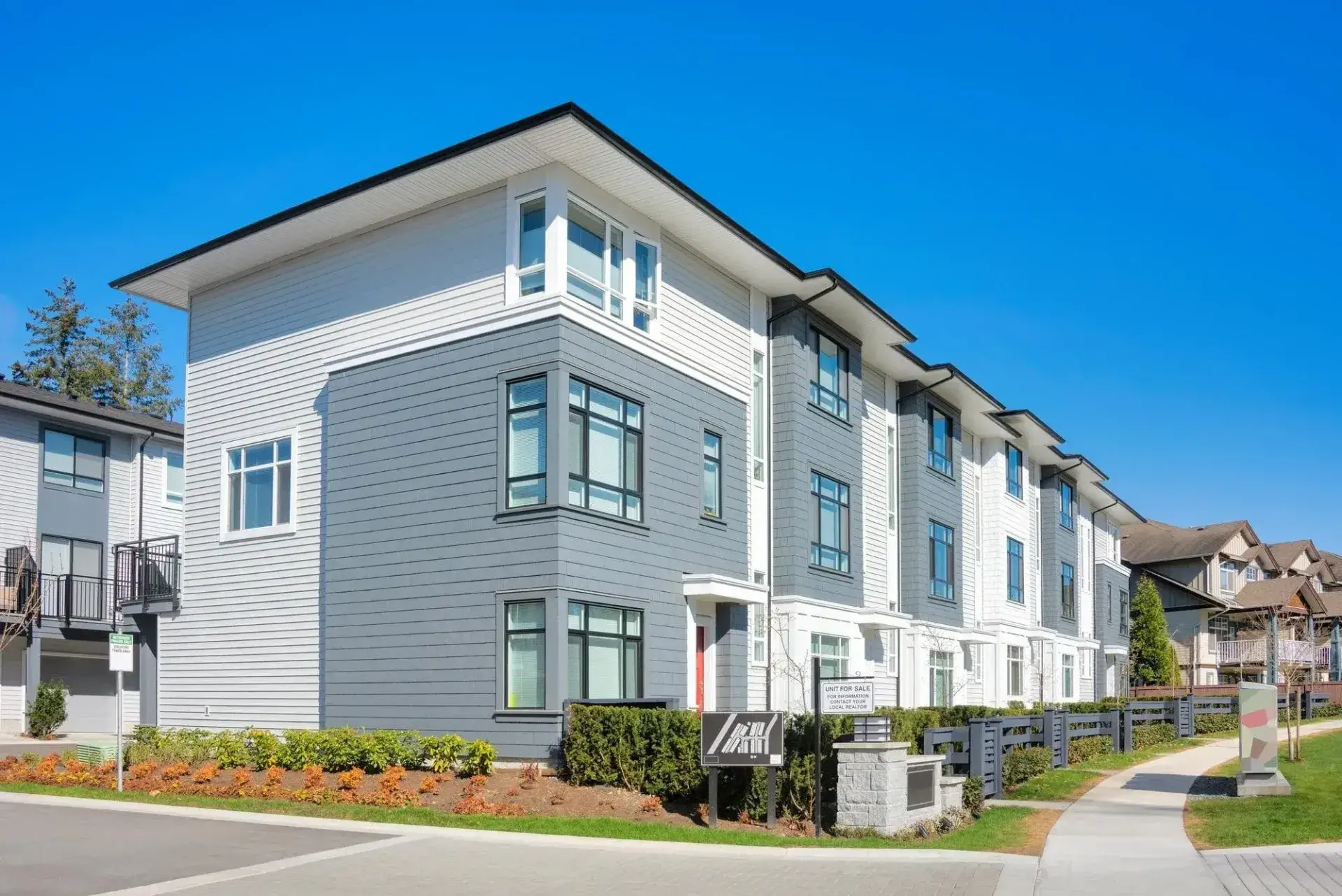 Modern multi-family apartment building with clean gray and white siding under a bright blue sky. The image represents smart, scalable property investments available through Investment Loans from Chris Lewis Home Loans.