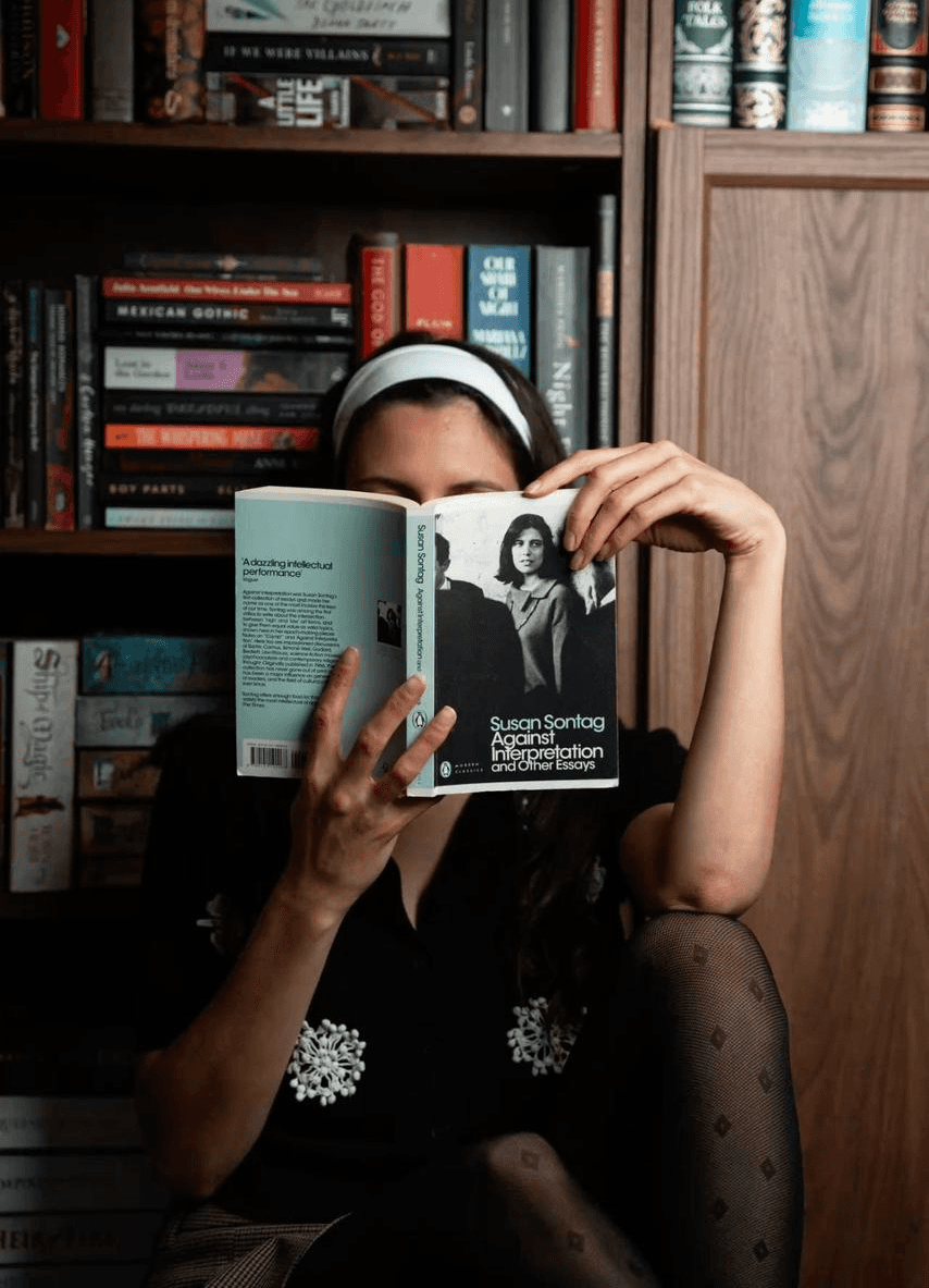 person reading book on brown wooden table taken at daytome