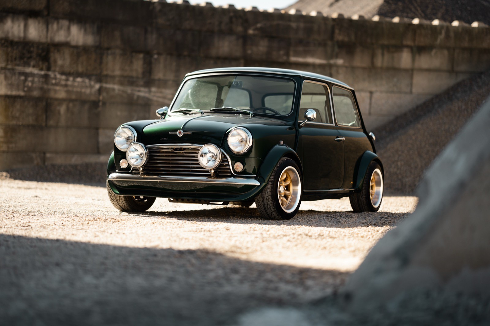 A small, green and black vehicle parked on a sandy surface, with a warm sunset lighting the scene.