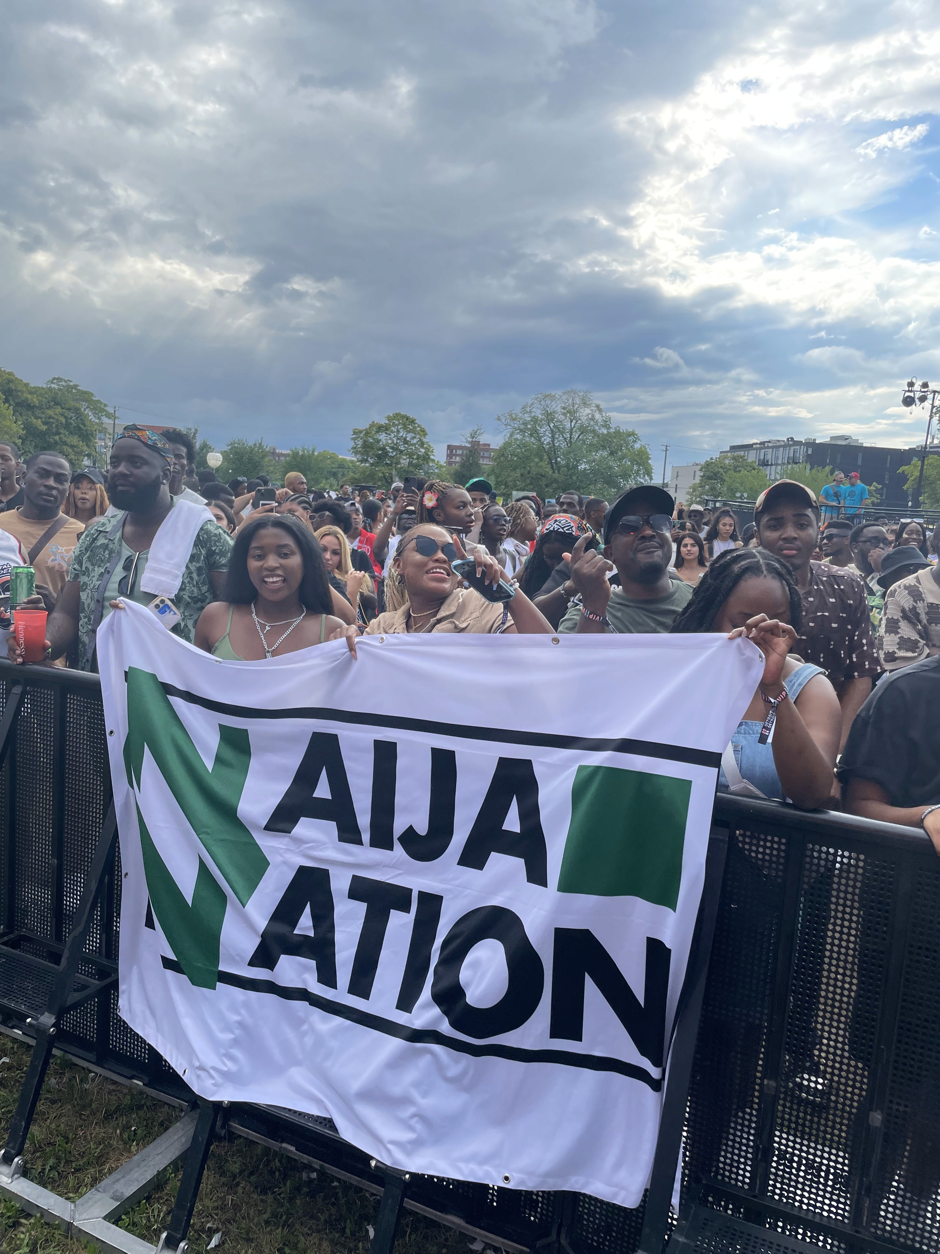 A festival crowd holds up a large Naija Nation banner at Afro Nation, a media partnership project by Tiffany Onyeyiriuche.