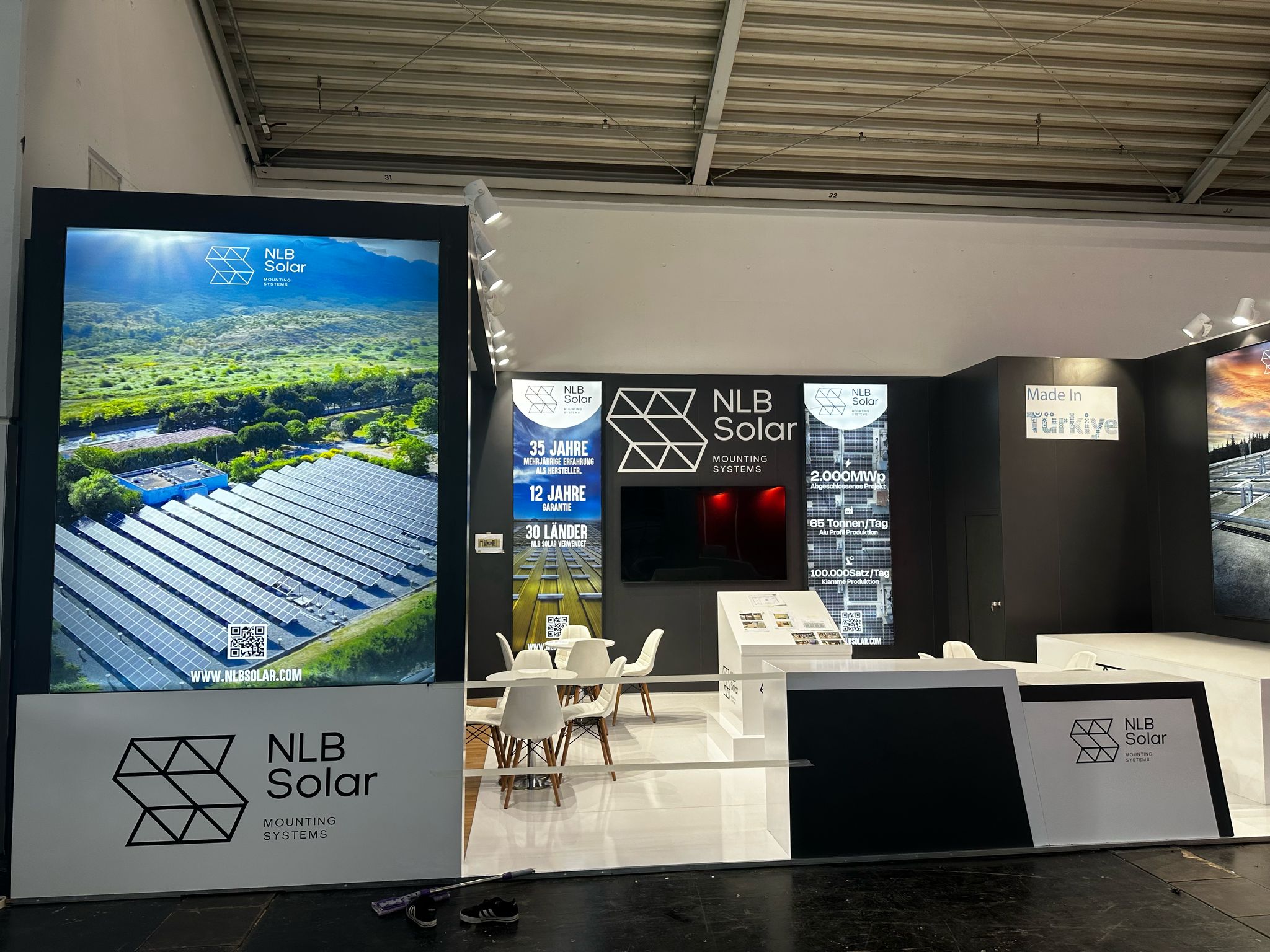 NLB Solar exhibition stand at Intersolar 2025 Munich, featuring a modern black-and-white design with illuminated graphic panels and product displays.