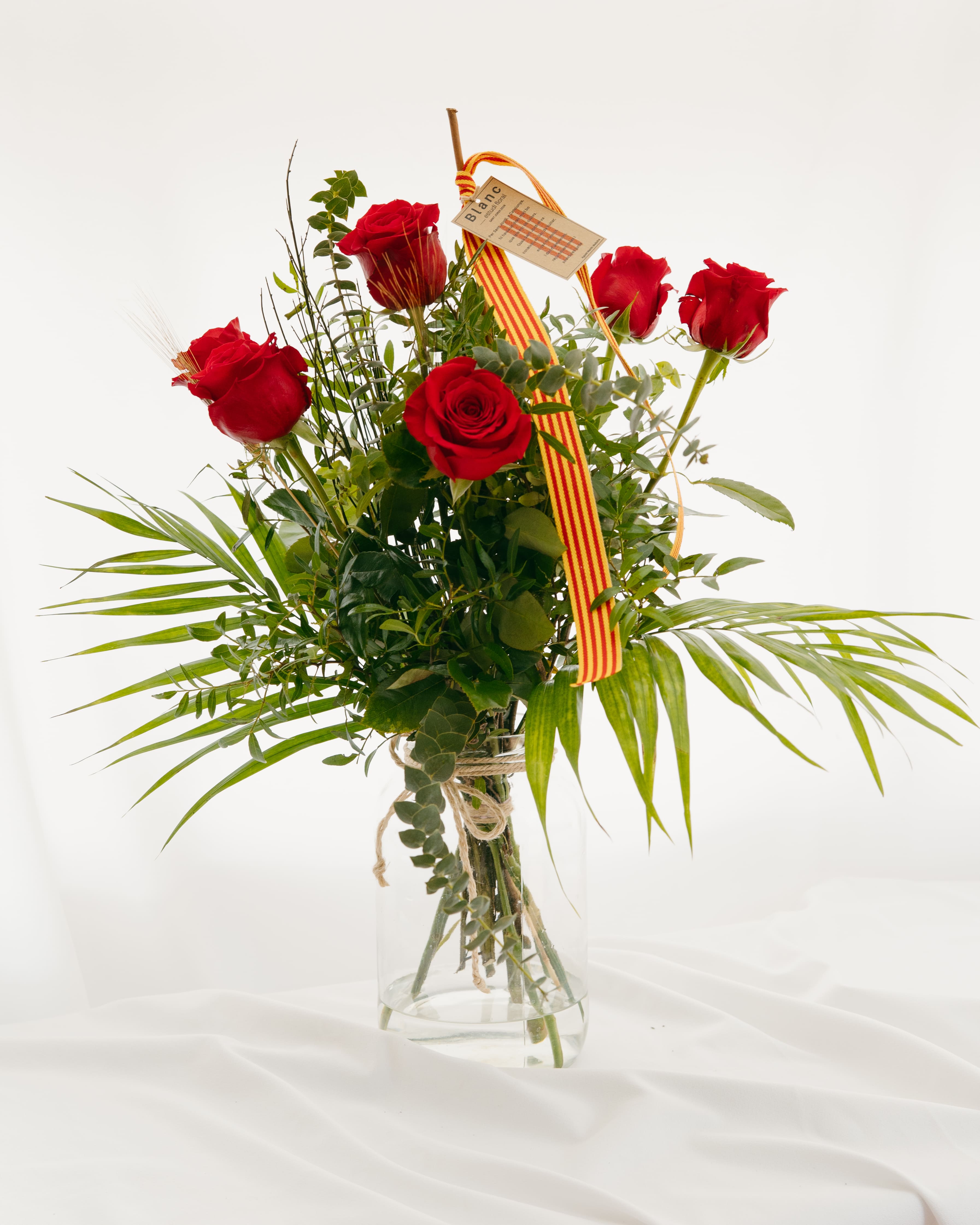 Ram de 12 roses vermelles de Sant Jordi amb eucaliptus, espigues i cinta de la senyera en gerro de vidre, creat per Blanc Estudi Floral.