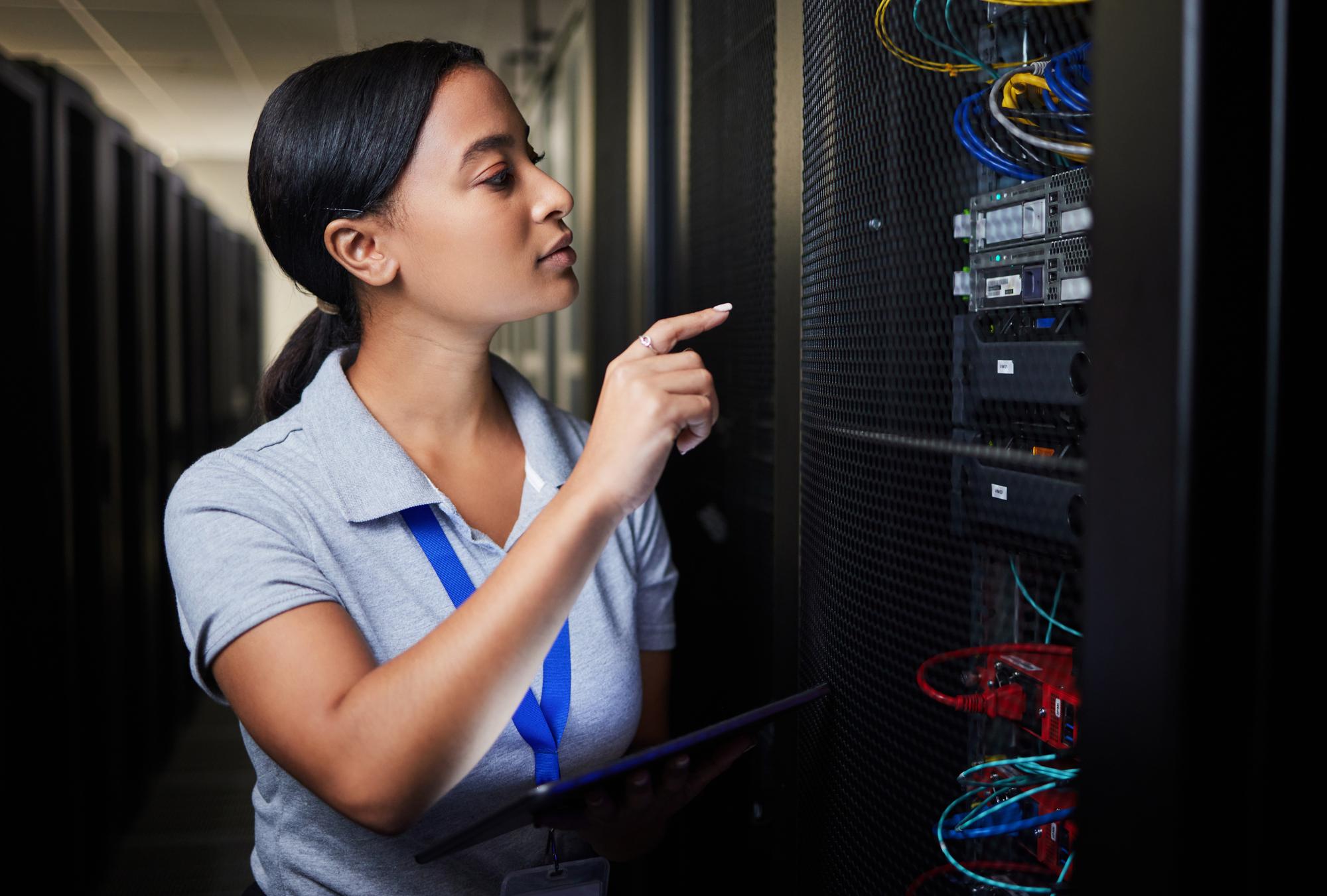 A woman examines the contents of a server rack in a data centre