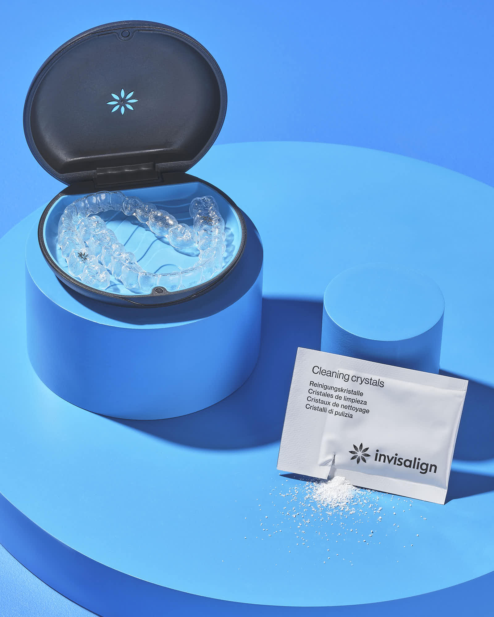Invisalign aligners with cleaning crystals on blue background.