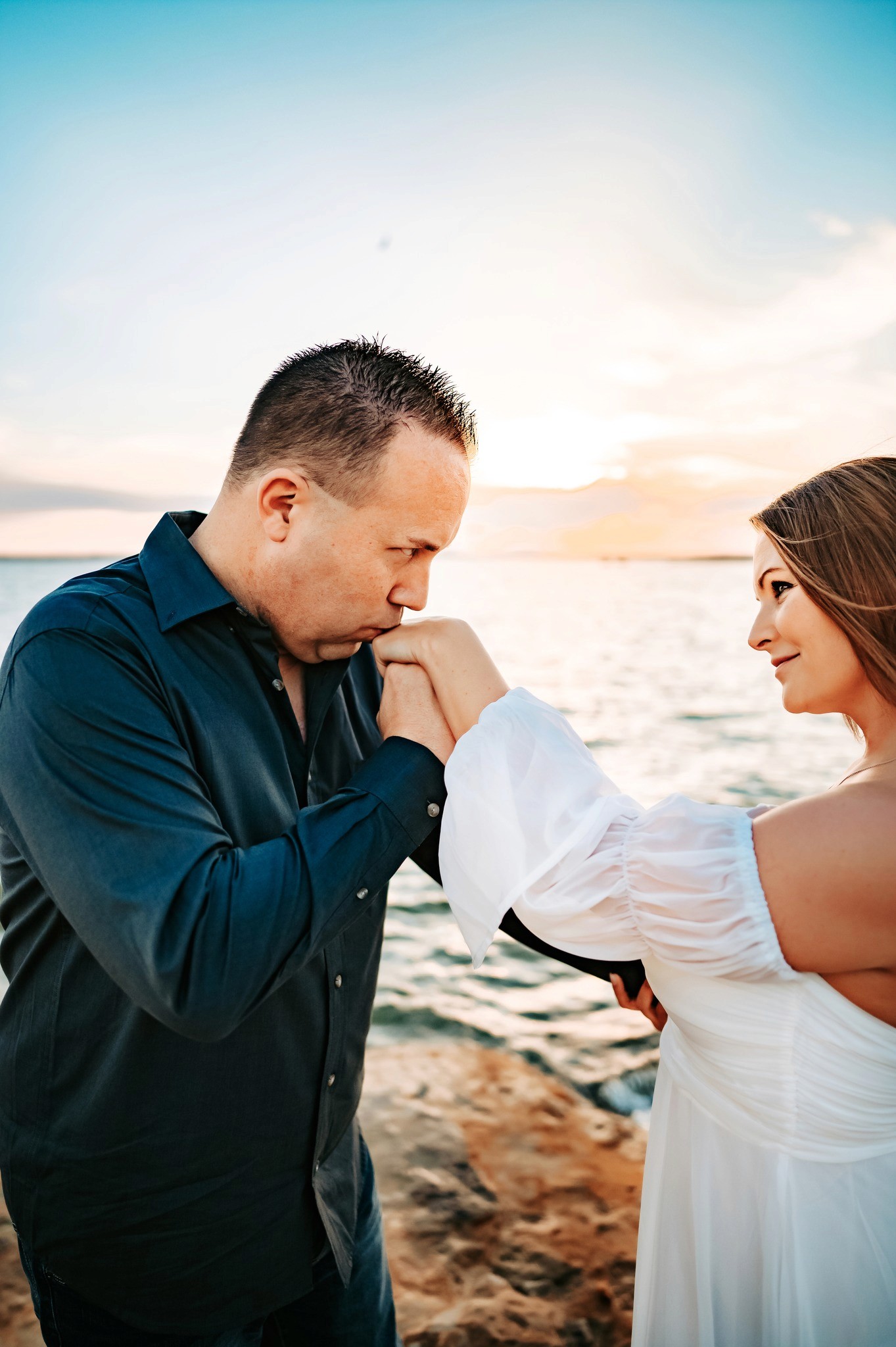 A person with shoulder-length blonde hair wearing a black newsboy cap and a black sweater.