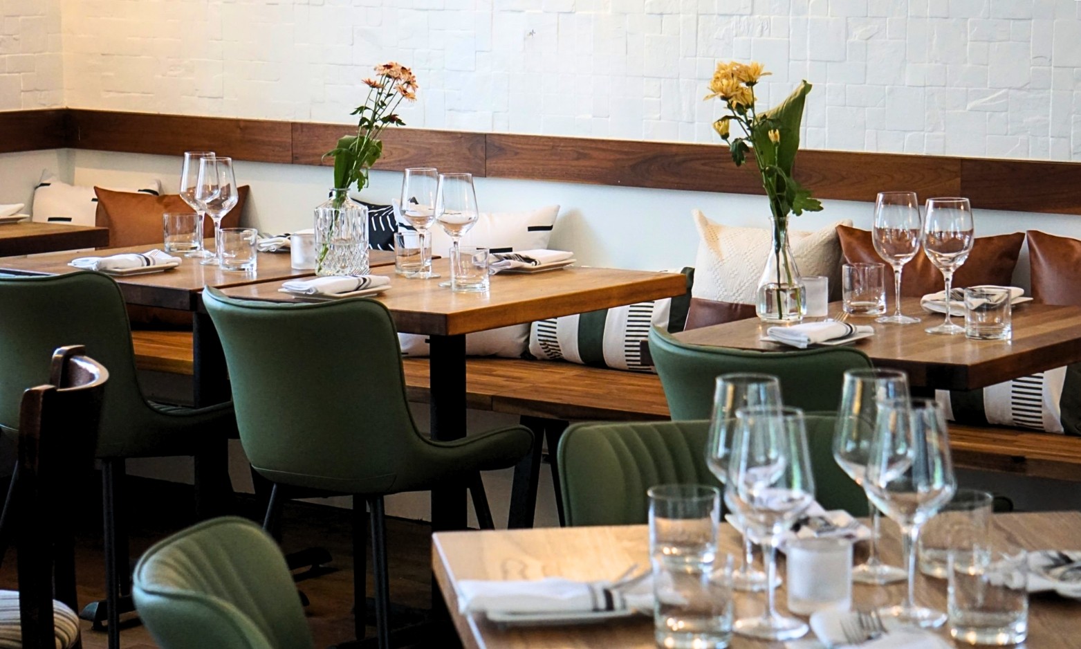Restaurant bar with guests seated at tables and bartenders at work.