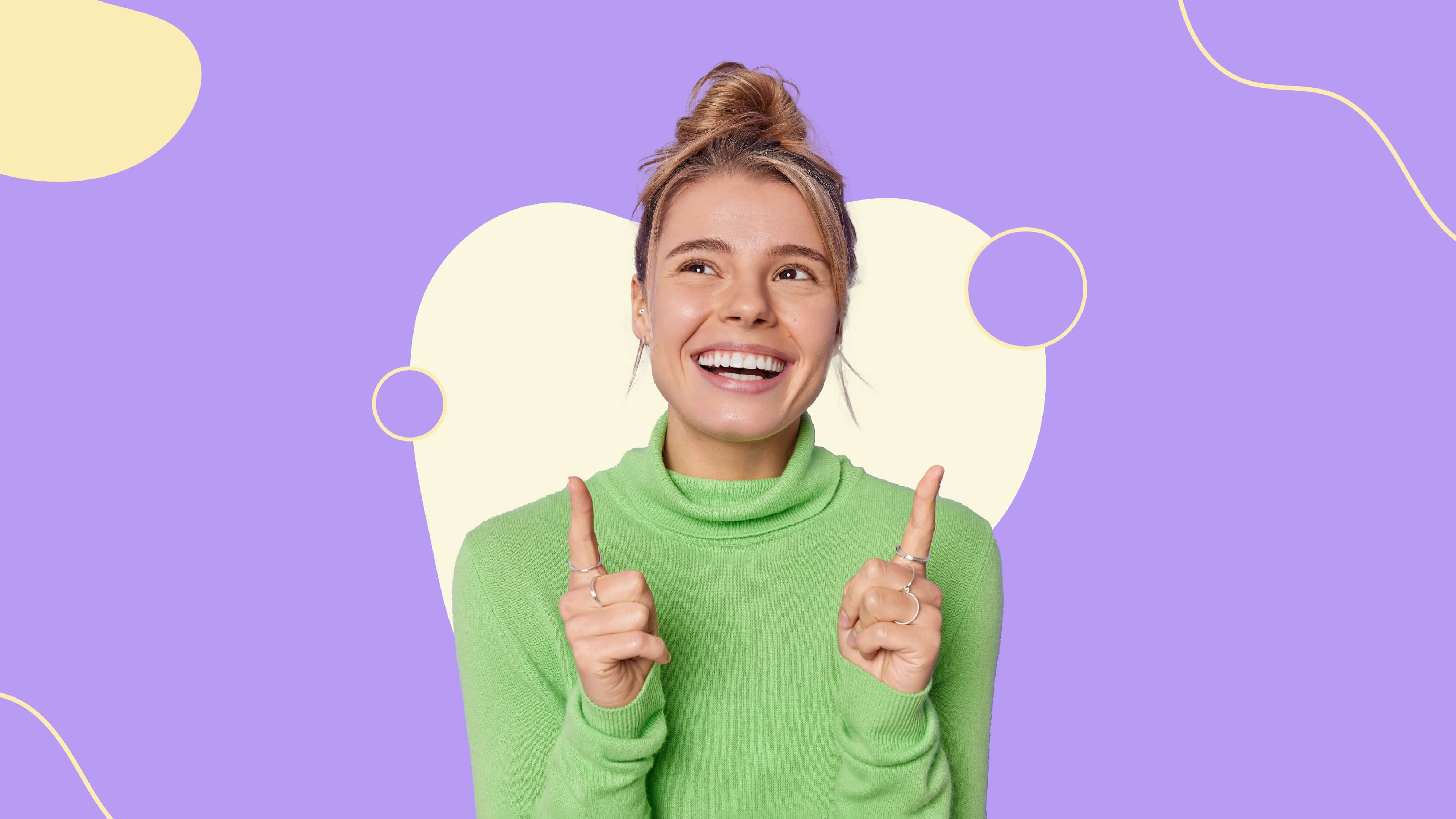 Woman in a green long sleeve, happily pointing up.