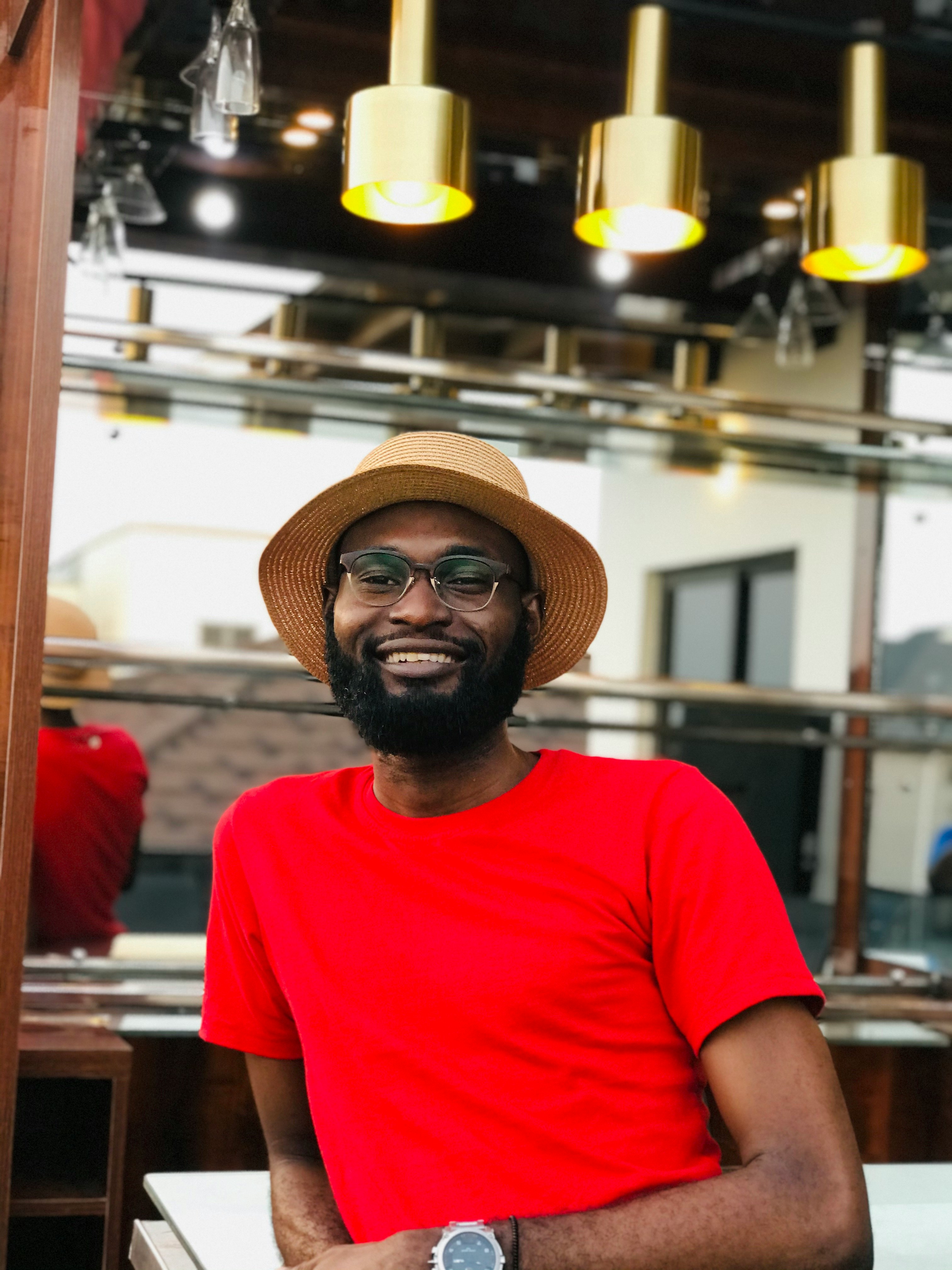 man in red crew neck t-shirt wearing brown fedora hat