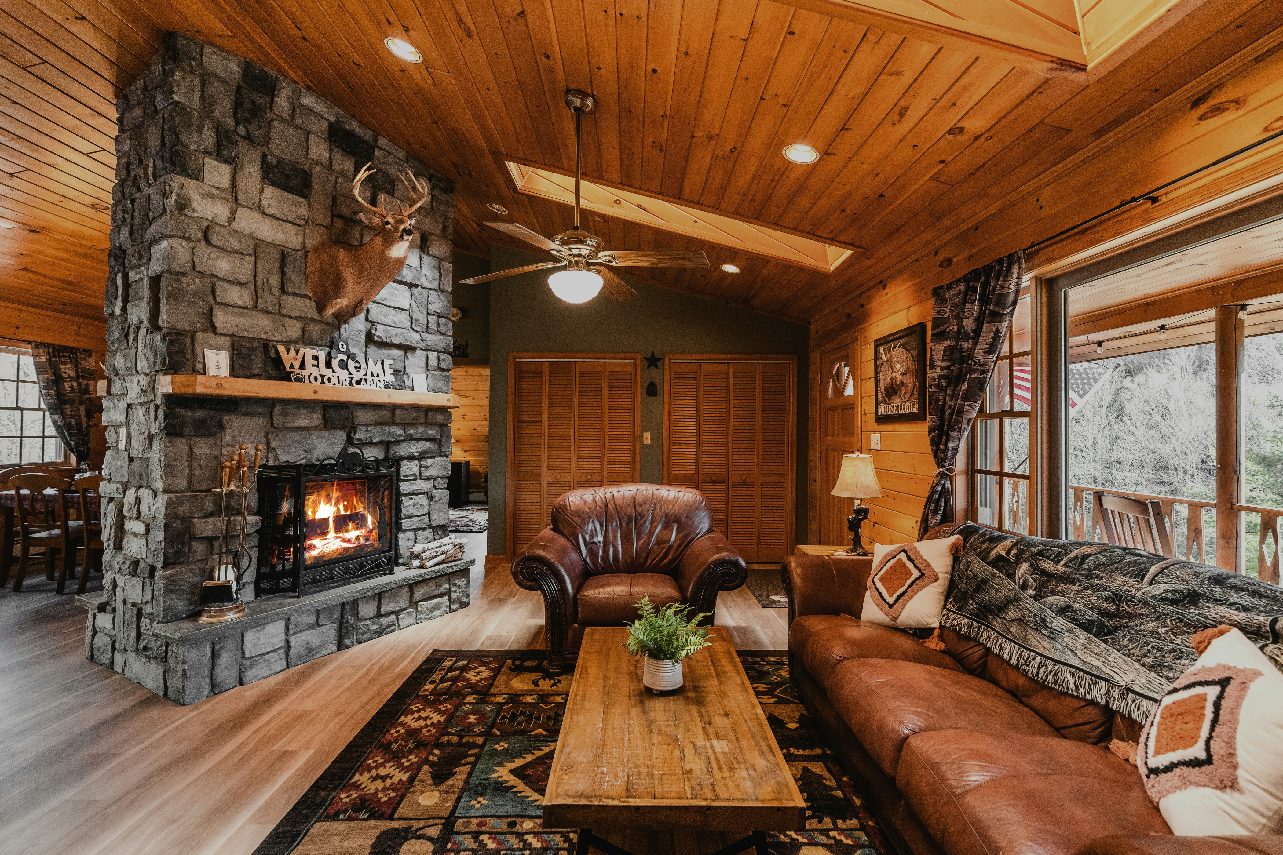 A log cabin living room with a stone fireplace and leather chairs