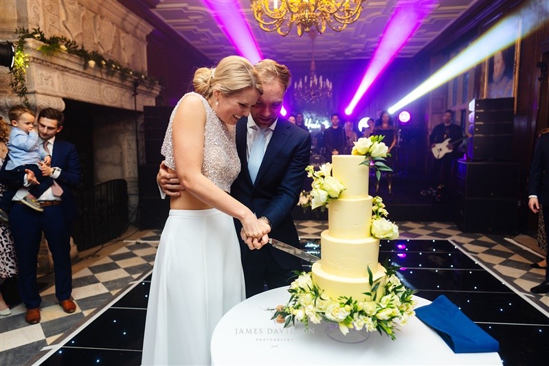 Maddy and Toby cutting their wedding cake beside the starlit dancefloor
