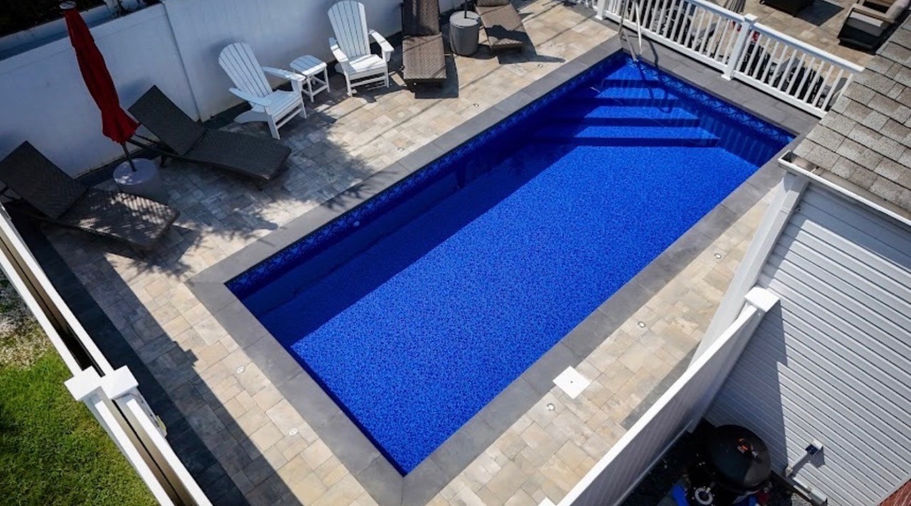 Rectangular blue in-ground pool with paver deck by CMC Masonry on Long Island