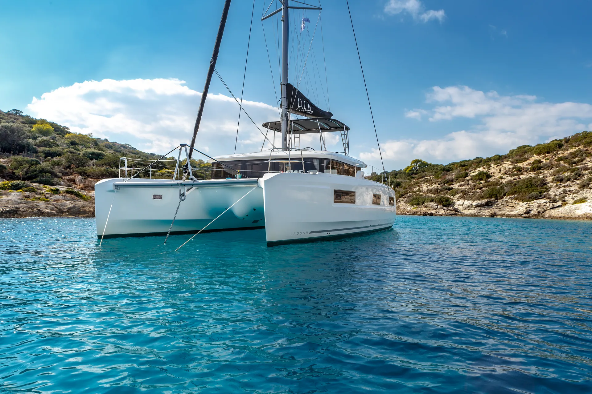 White Rock 36 speedboat with captain at helm cruising calm blue waters near Paros coastline with hills in background.