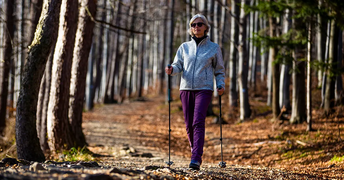 Bilde av en voksen kvinne som går tur med staver