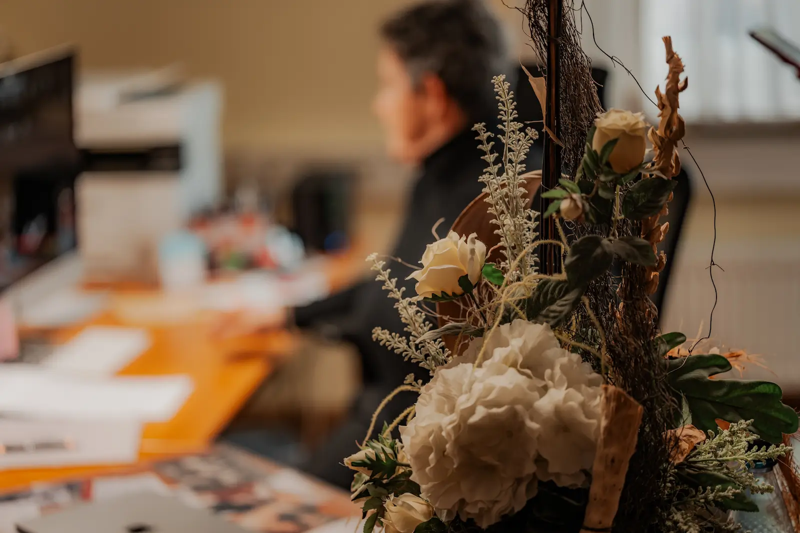 Scharf zu sehen ist ein Blumengesteck im Vordergrund und unscharf im Hintergrund Simone Rauschenbach