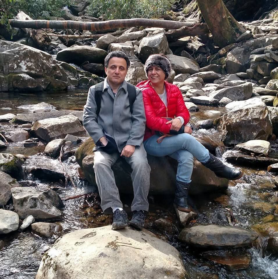 Couple posing in nature behind them a creek