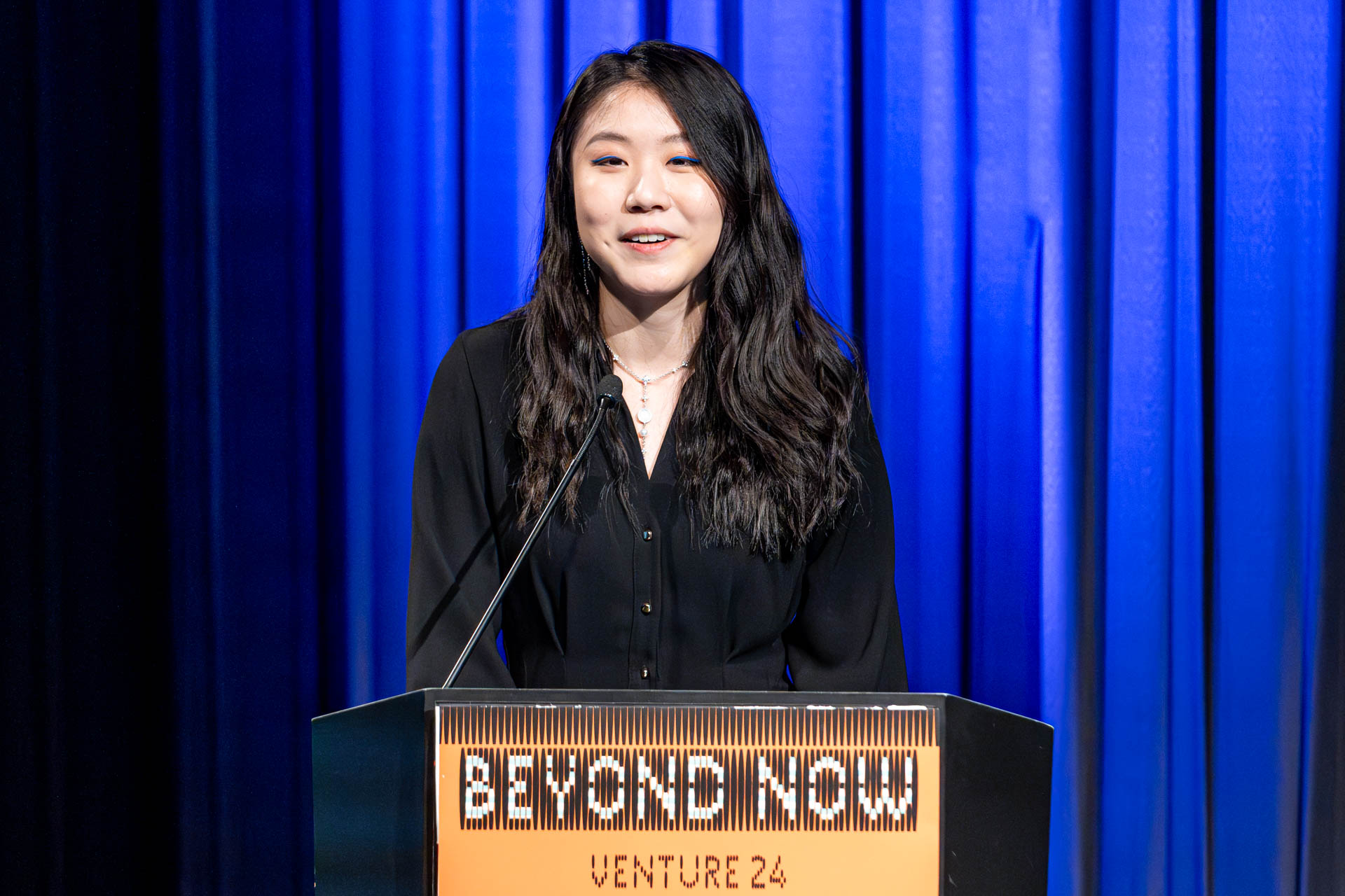 a student at a podium presenting a project in a Theatre