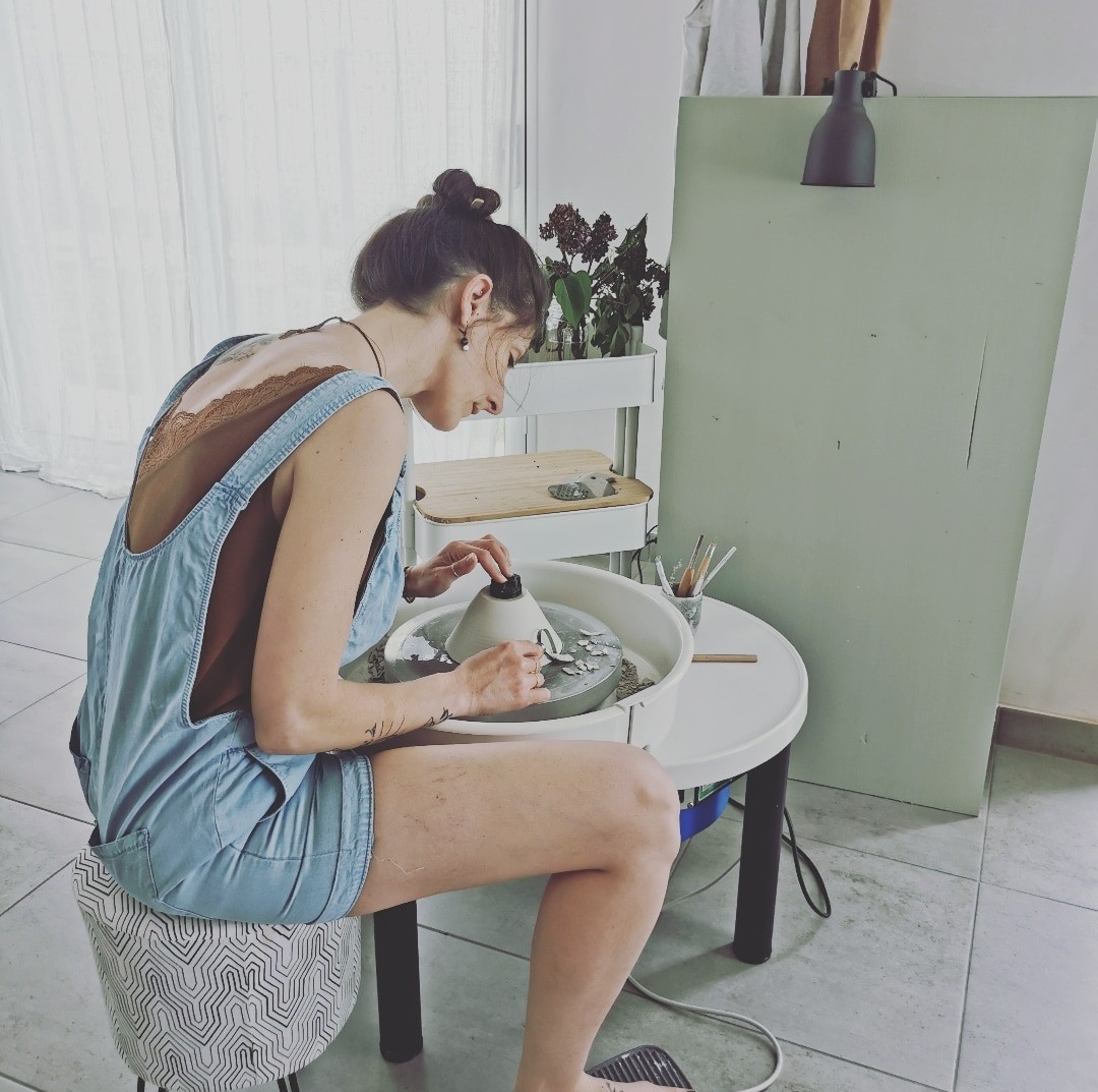 Céramiste au tour de potier dans son atelier, tournage d'une pièce en argile.