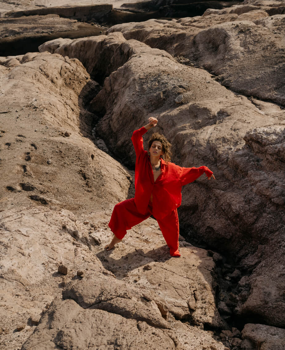 Blertë Dibrani tanzend mit rotem Hemd auf einem Felsen