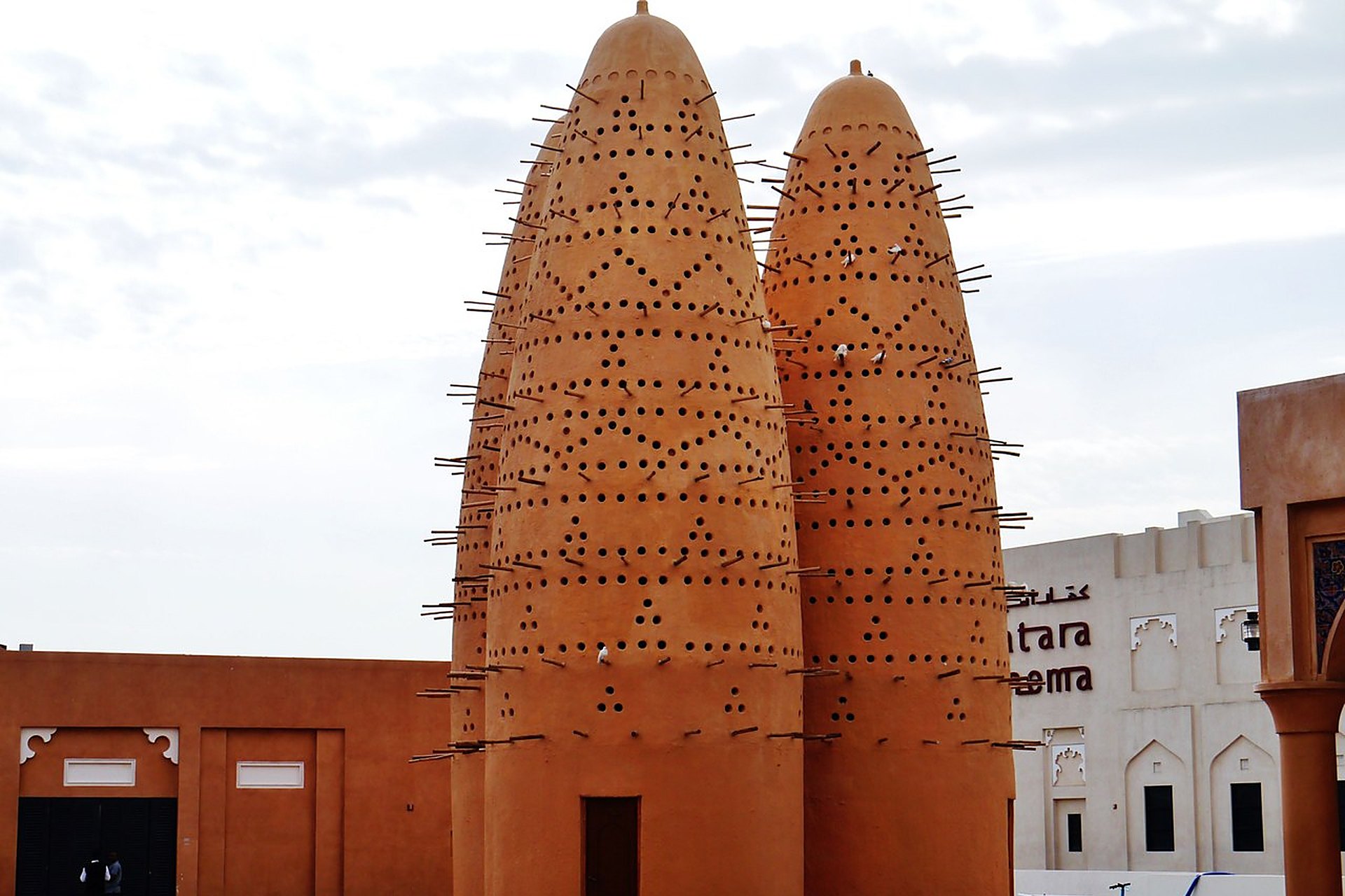 Deux des tours à pigeons de Katara, à Doha, en argile ocre percée de trous et hérissée de perchoirs en bois