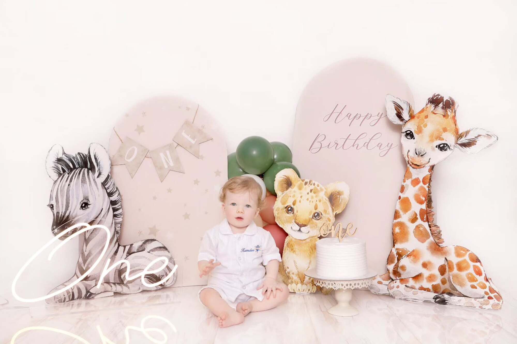 Baby excitedly sitting beside a smash cake, full of curiosity and wonder, captured by Mahvin Photography in Dubai studio.