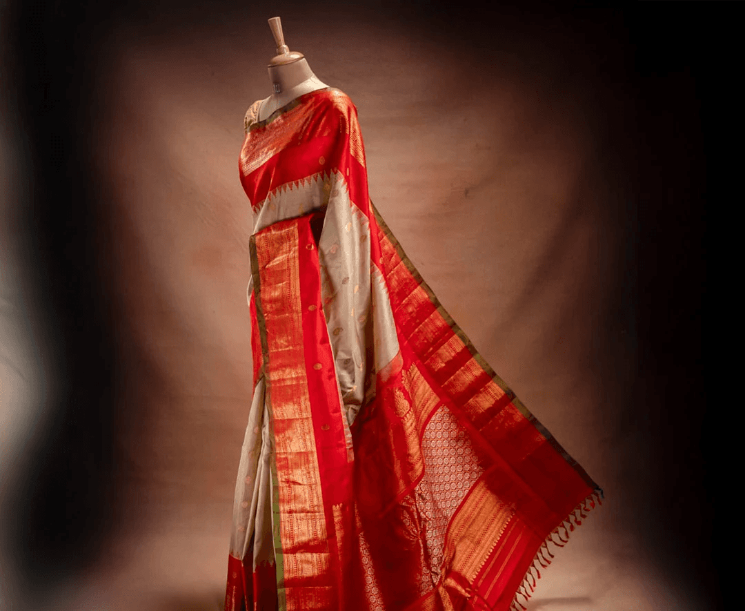 A golden Gadwal saree with rich red borders from That Saree Shop, draped on a mannequin to highlight its intricate zari weaving, silk-cotton texture, and regal South Indian craftsmanship.