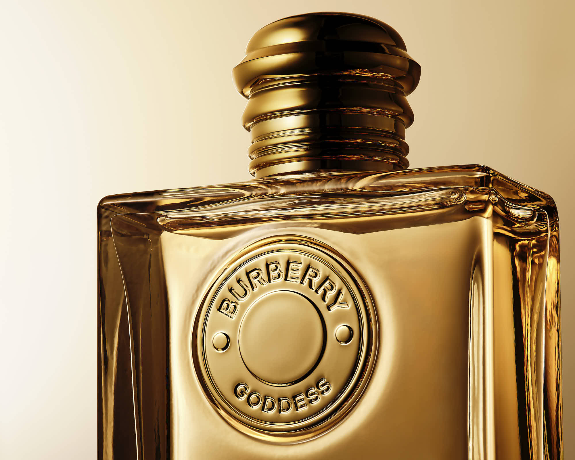 A close-up of a golden perfume bottle with a decorative cap and detailed label against a soft, warm background.