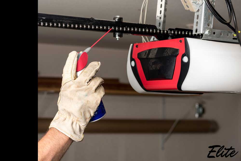Applying lubricant to a garage door opener chain during winter maintenance in Northwest Arkansas. | Elite Garage Door | Northwest Arkansas Garage Door Repair & Installation