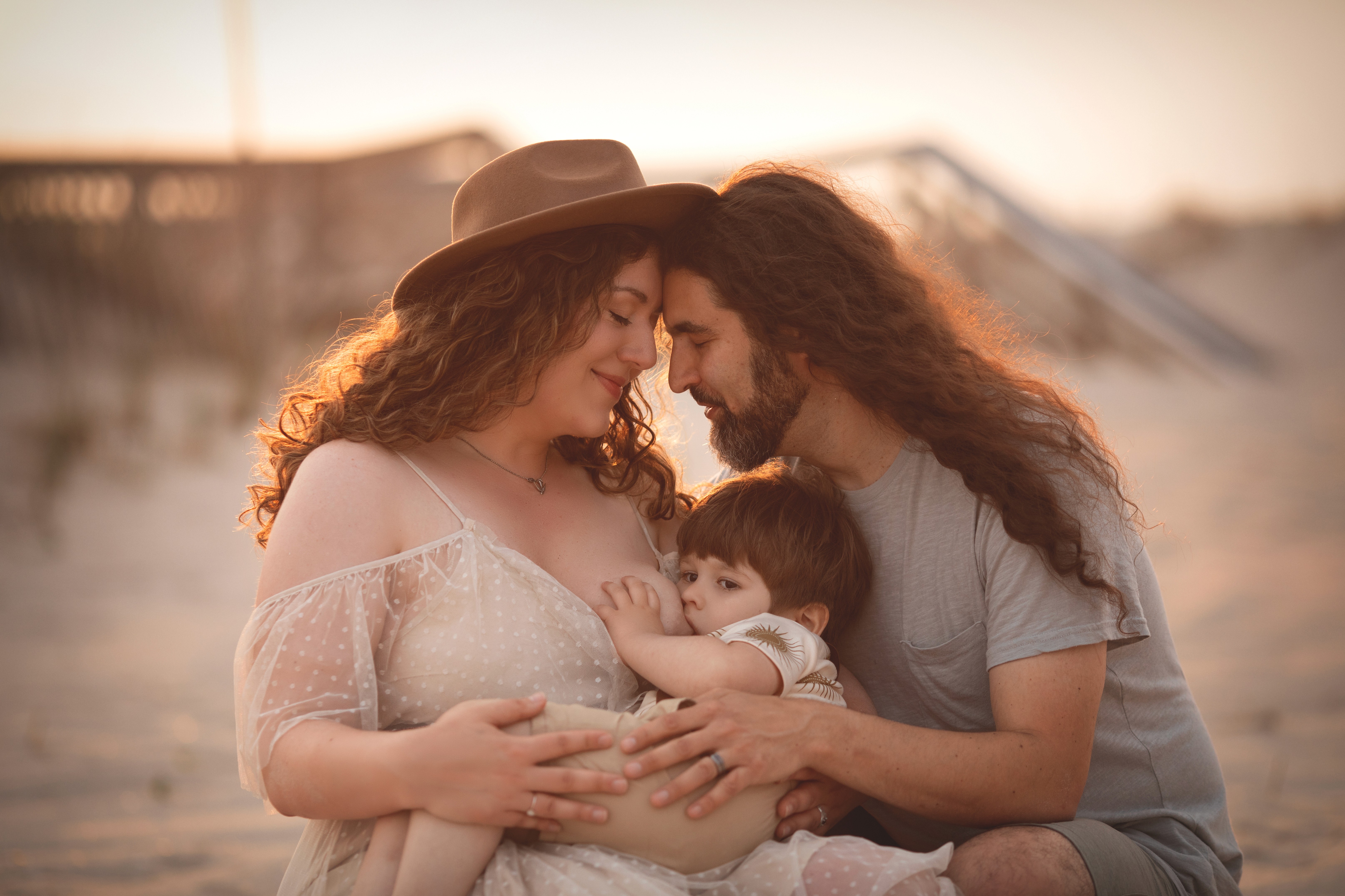 Mom and Dad sitting with her young child by the ocean, captured in a calm documentary-style moment.