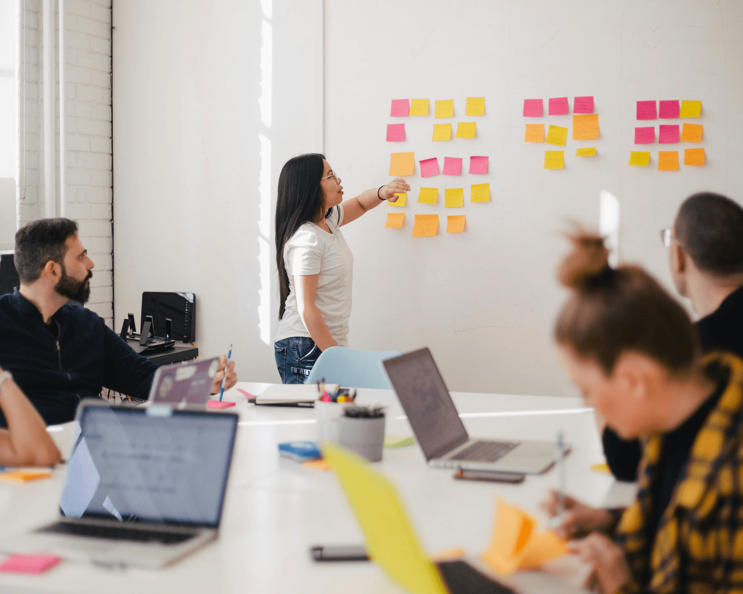 Photo of a woman presenting post it notes in a large meeting room. Photo by Jason Goodman.