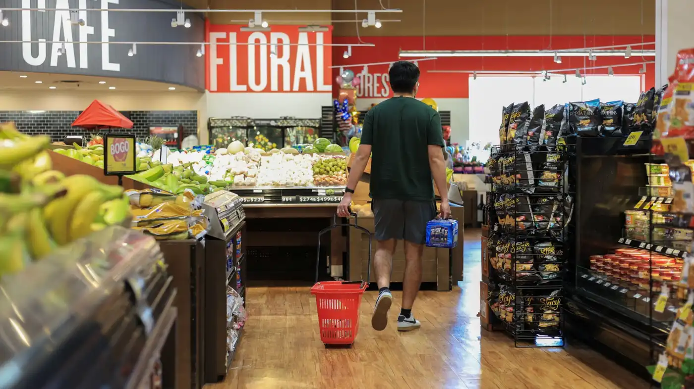 A shopper comparing grocery prices in a supermarket, illustrating the impact of inflation on everyday household expenses.