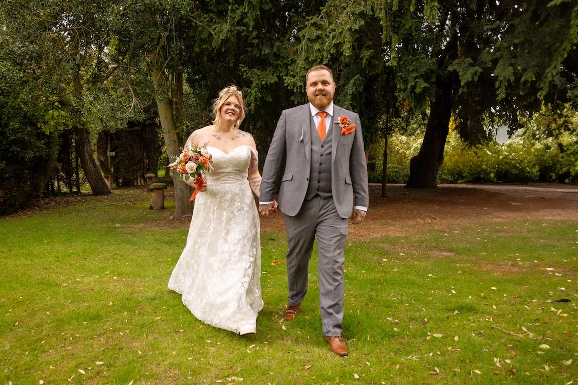 Hannah and Shawn walking hand in hand through the gardens at the Charlecote Pheasant Hotel