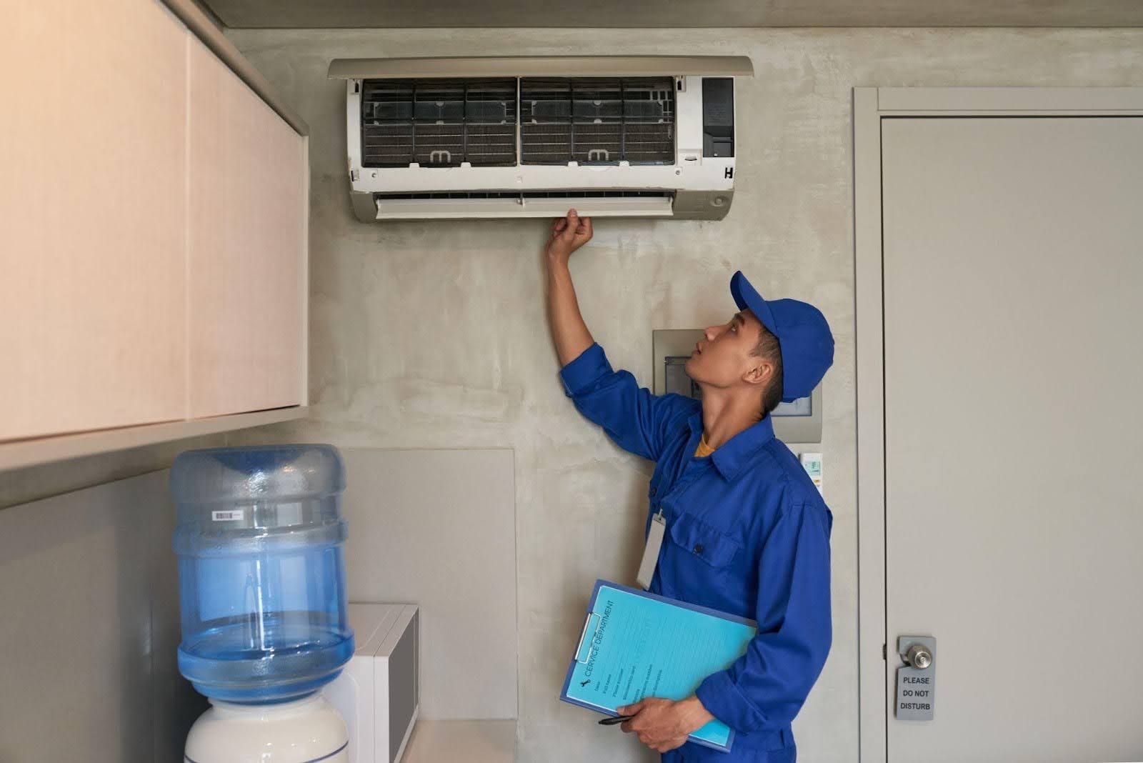 Technician in blue uniform inspecting HVAC unit in Chilliwack, Fraser Valley, British Columbia for plumbing.