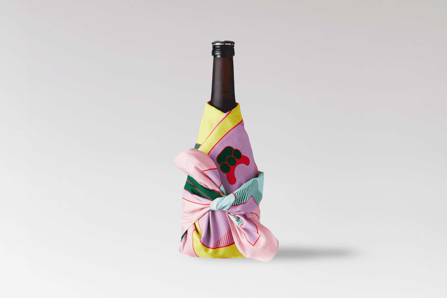 Bottle wrapped in the colorful Wrap a Tale furoshiki designed by Josephine Grenier, featuring illustrations inspired by Japanese folklore.