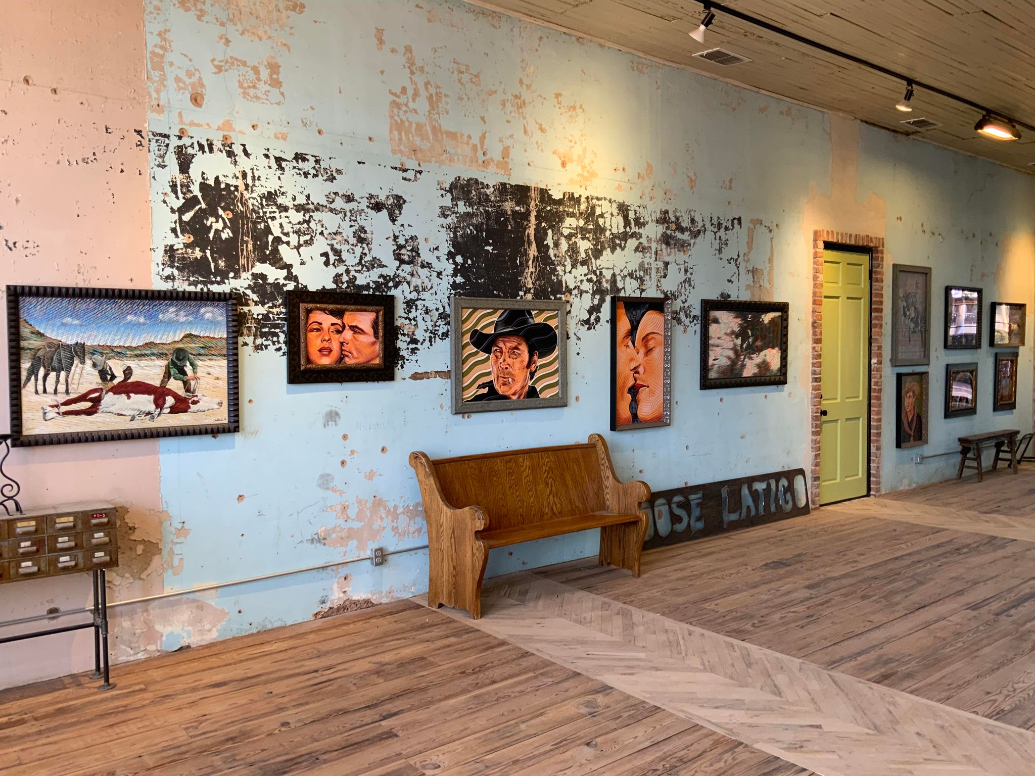 The interior of the gallery with paintings hanging along a wall