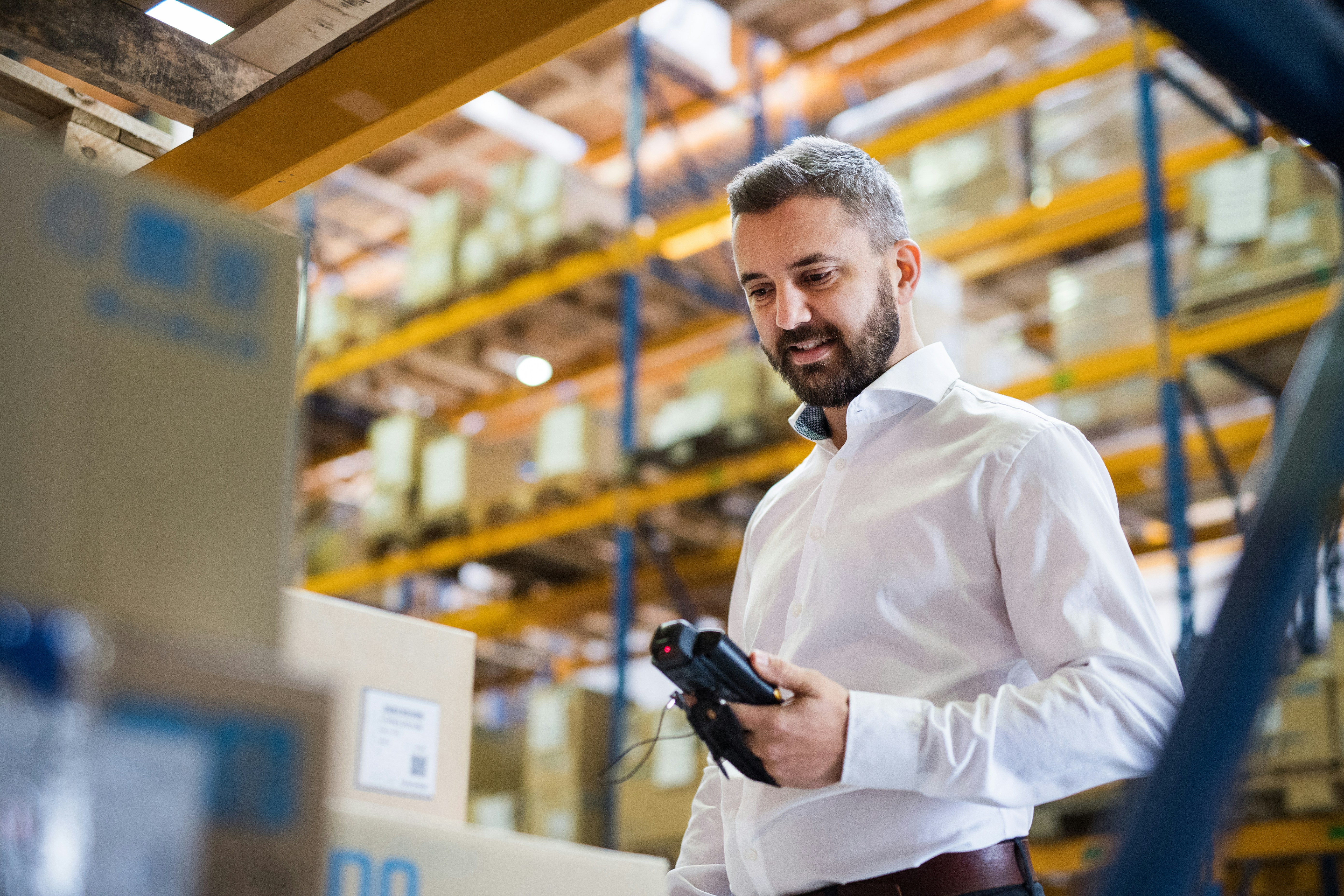 man checks boxes with a bardcode scanner in a warehouse