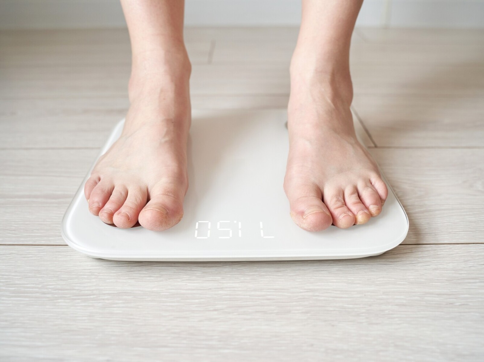 person standing on a scale to check their successful running and weight loss results