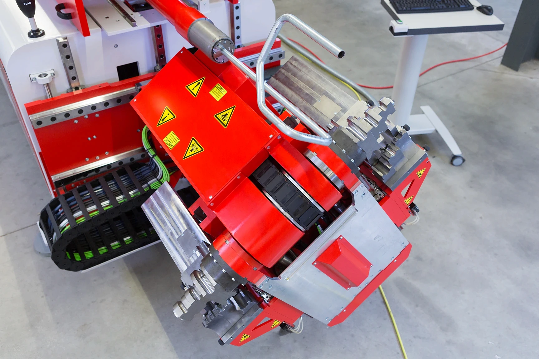 Tube bending machine forming curved metal tubing in an industrial workshop.