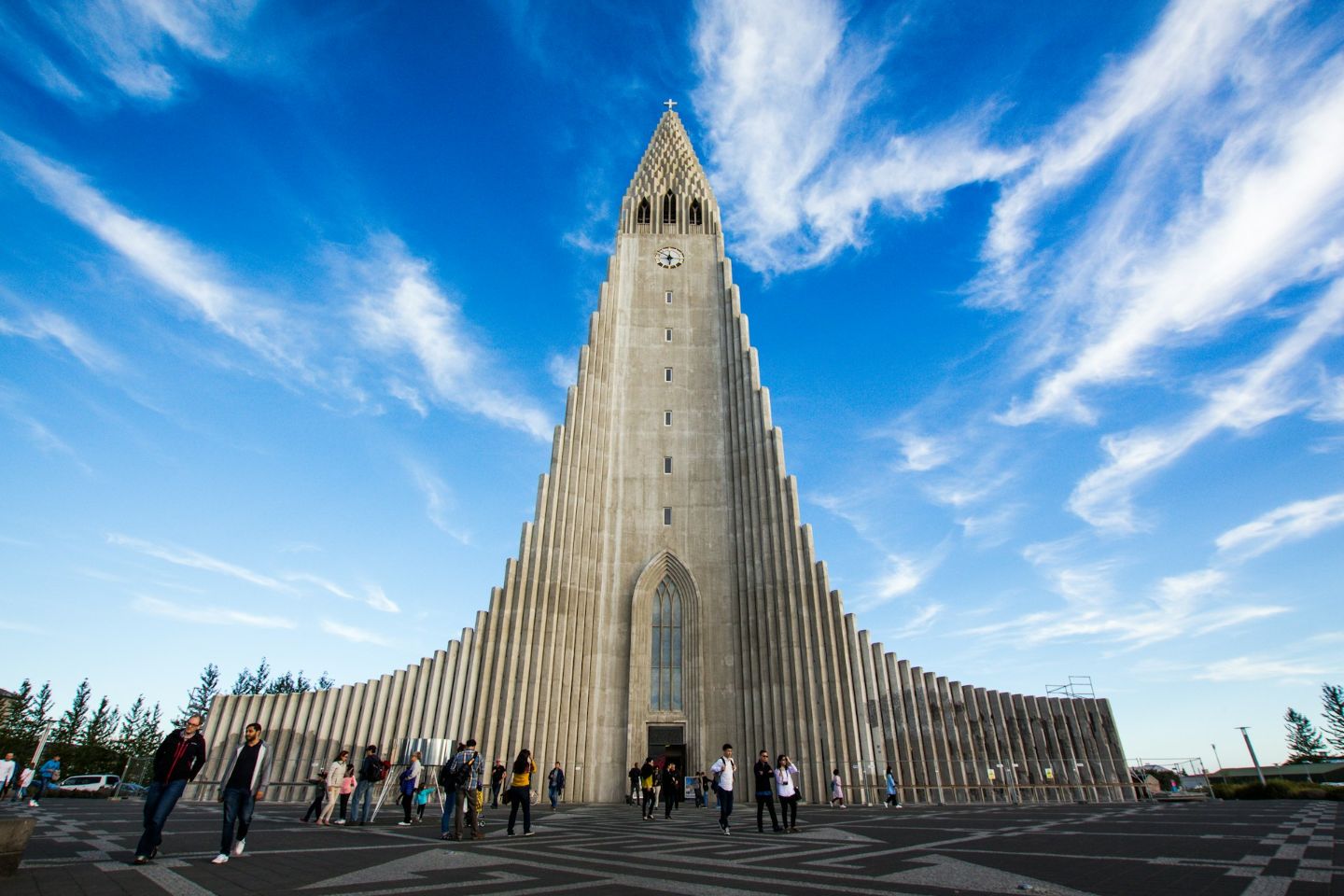 Front view of Hallgrímskirkja church in Reykjavík with visitors under a bright blue sky.