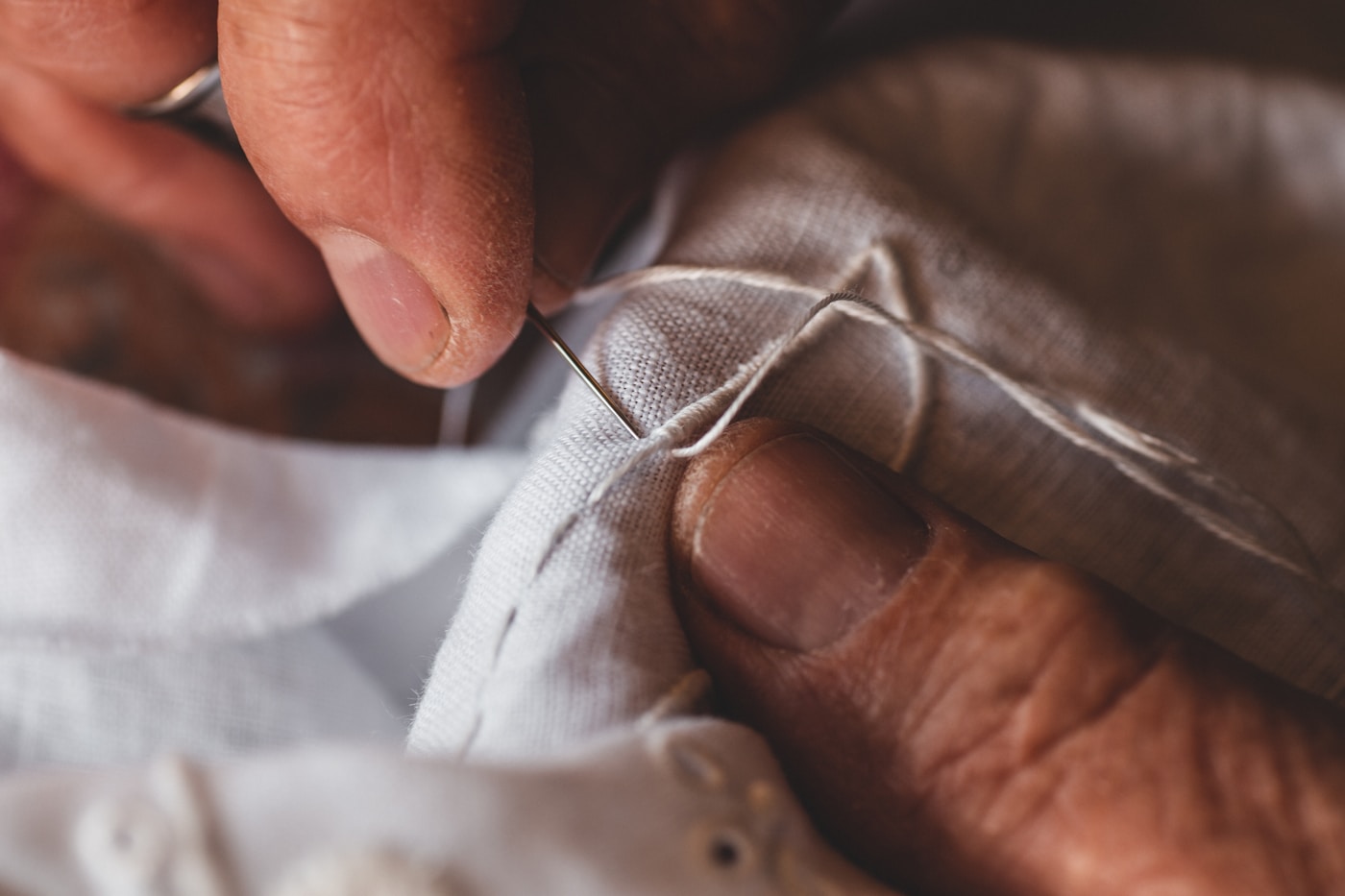 Hands mending fabric by needle and thread