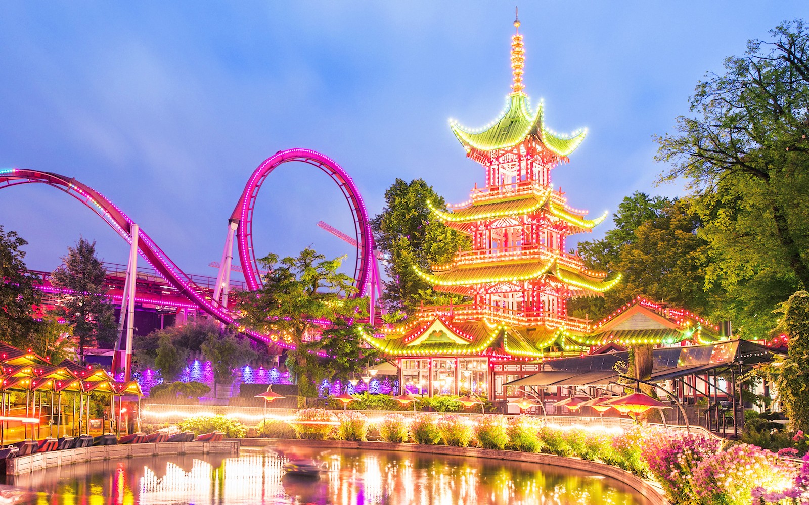 Tivoli Kertek megvilágított pagodája és hullámvasútja alkonyatkor.