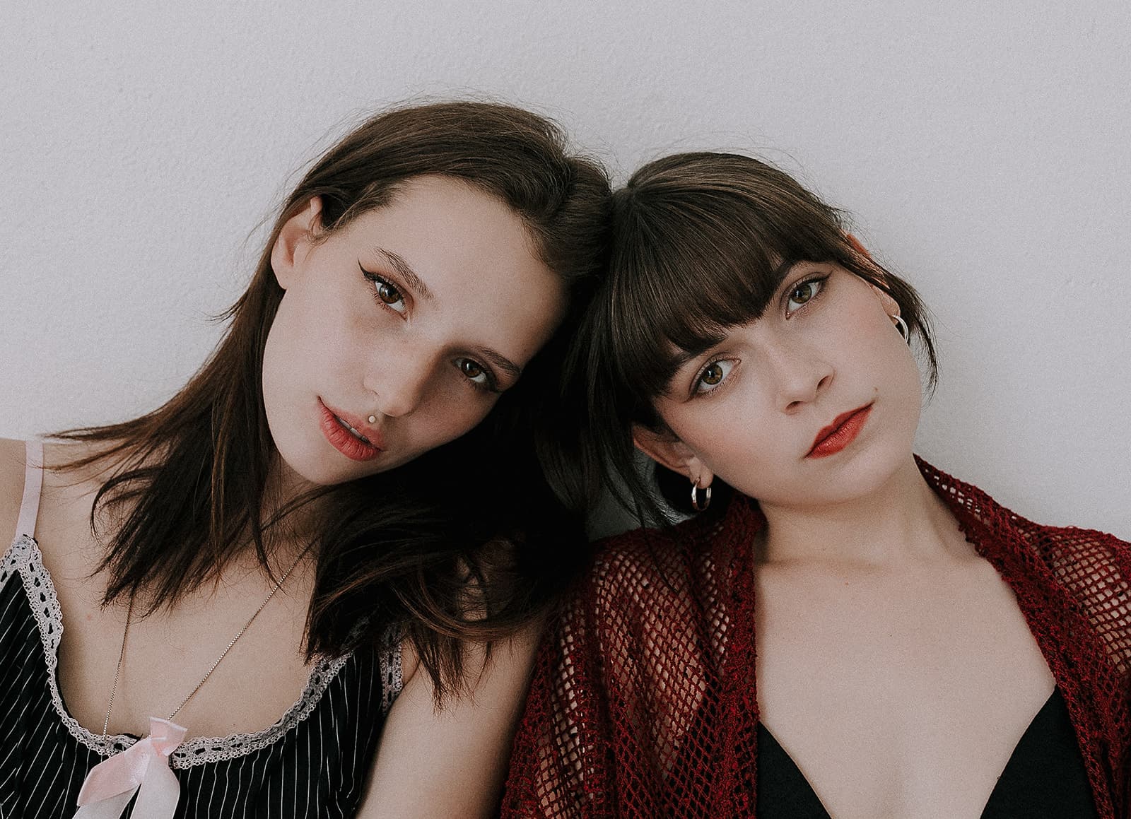 A close-up of two models with their heads resting together, both gazing softly into the camera during a 90s vintage photoshoot at Revelator Studio, a natural light studio in Shreveport.