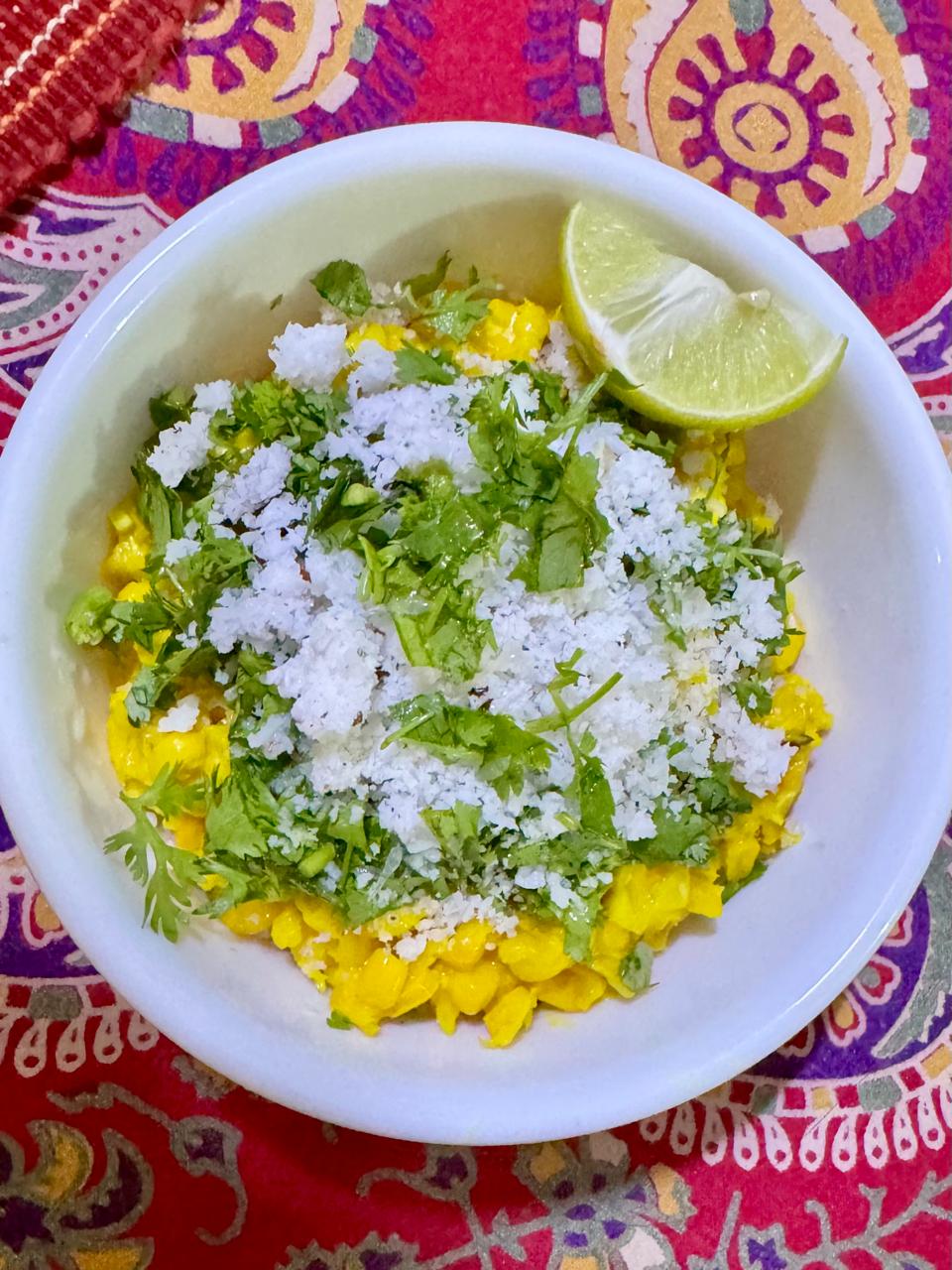 Bhutte ka kees garnished with coconut and coriander leaves and served with a wedge of lemon.